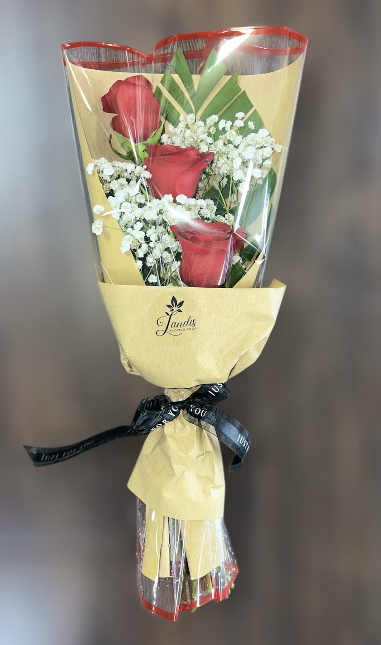 Bouquet of red roses and white baby's breath wrapped in yellow paper