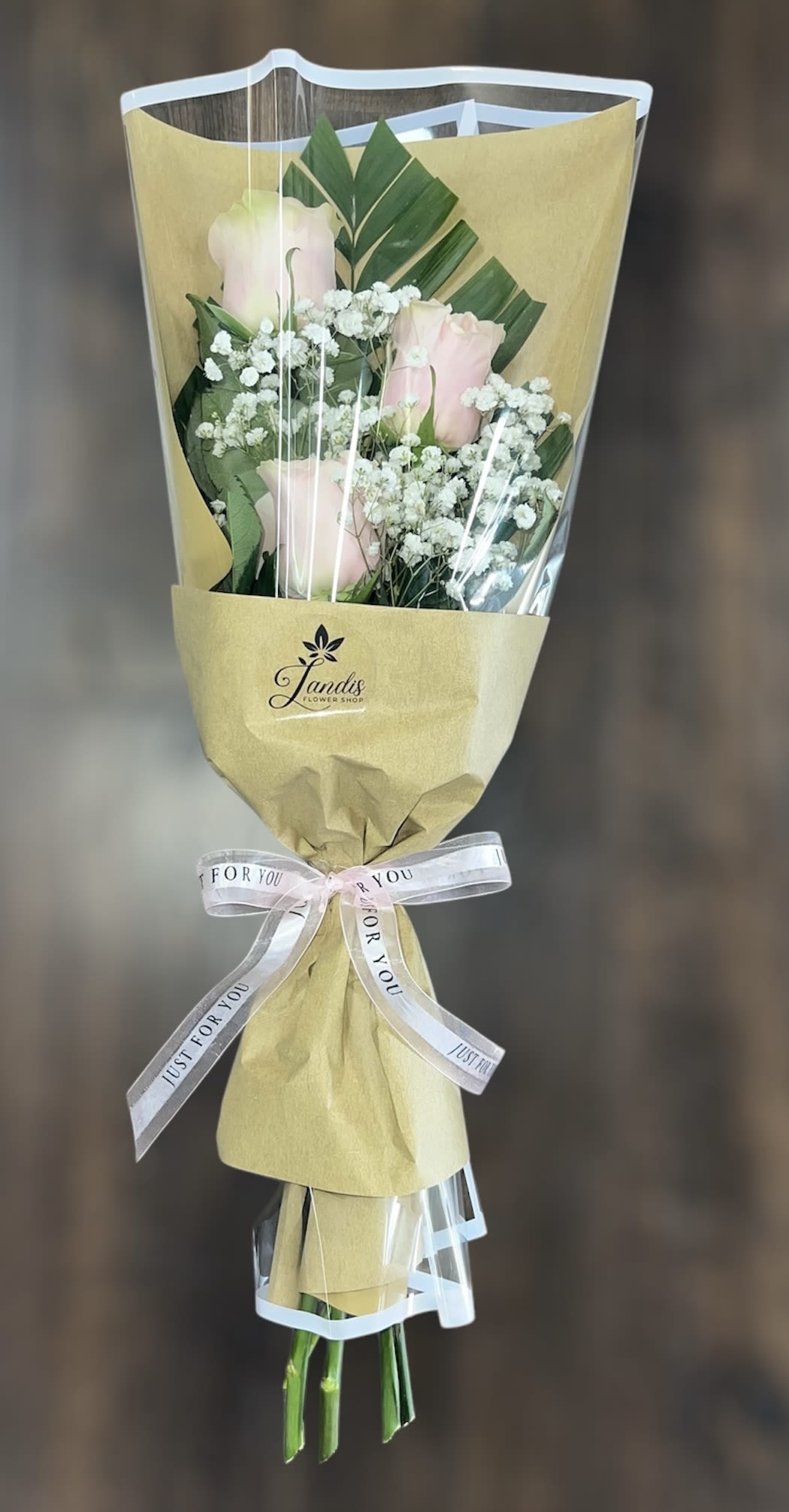 Bouquet of pale pink roses with white baby's breath in tan wrapping