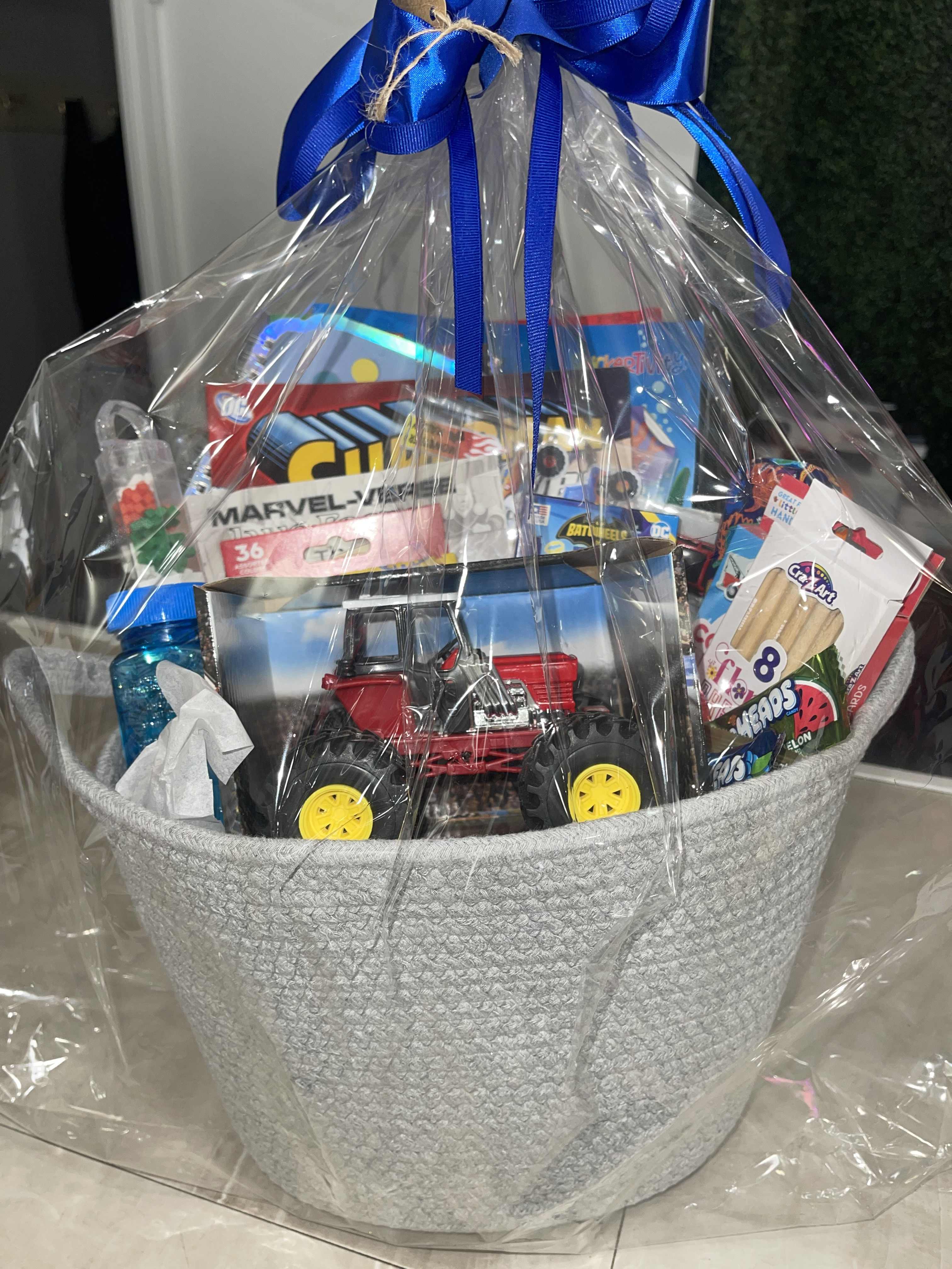 Gift basket with toys and candy wrapped in clear plastic and a blue ribbon