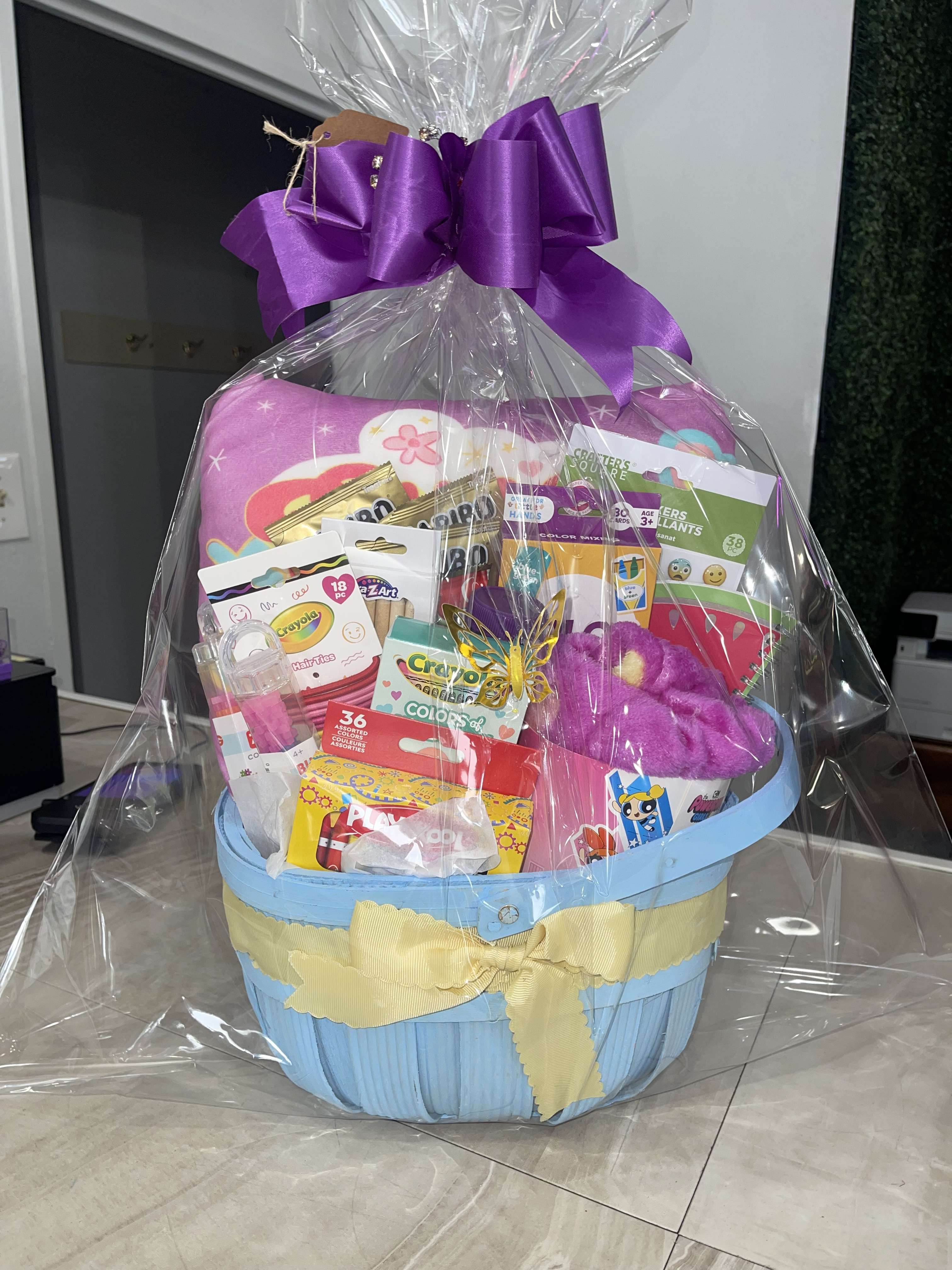 Gift basket with toys and candy wrapped in clear cellophane and a purple bow