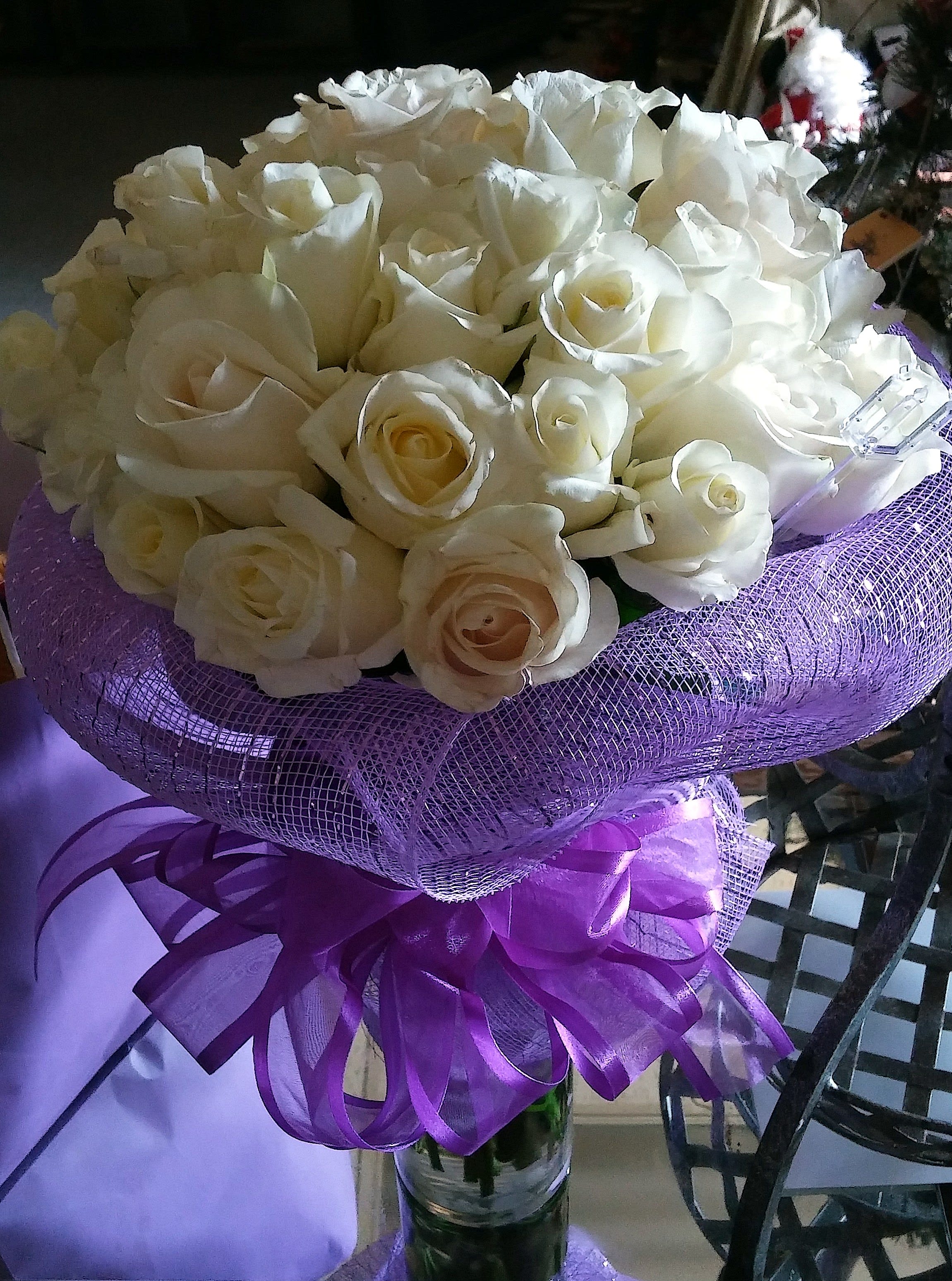 Bouquet of white roses wrapped in purple mesh with a ribbon