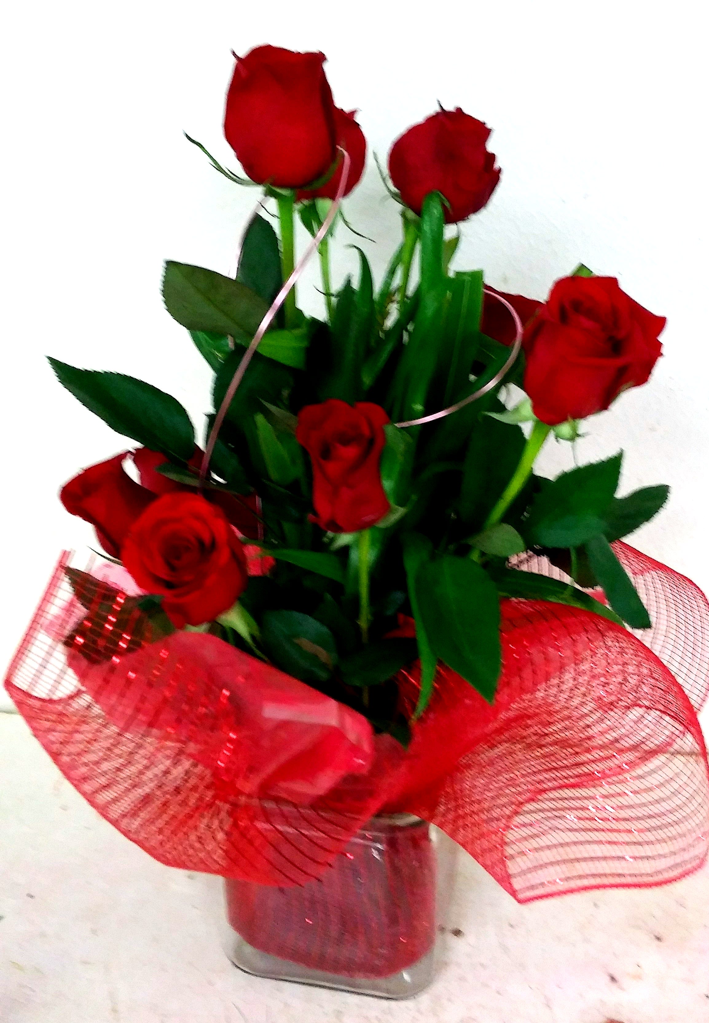 Bouquet of red roses in a clear glass vase with red mesh wrap