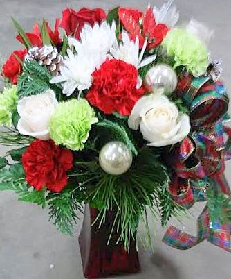 Red and white floral arrangement with ornaments and ribbon in a vase