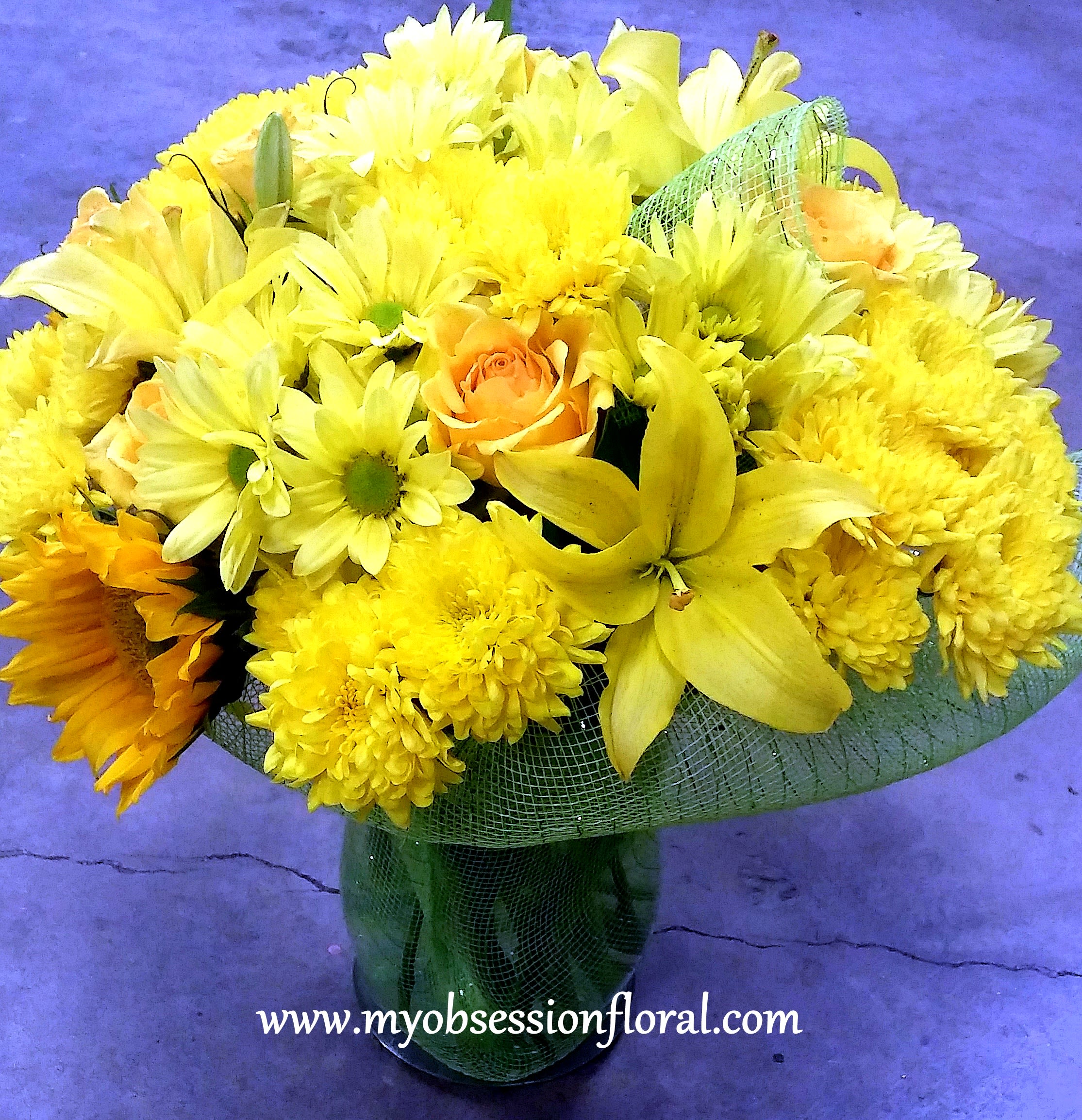 Yellow bouquet with daisies, chrysanthemums, and roses in a glass vase