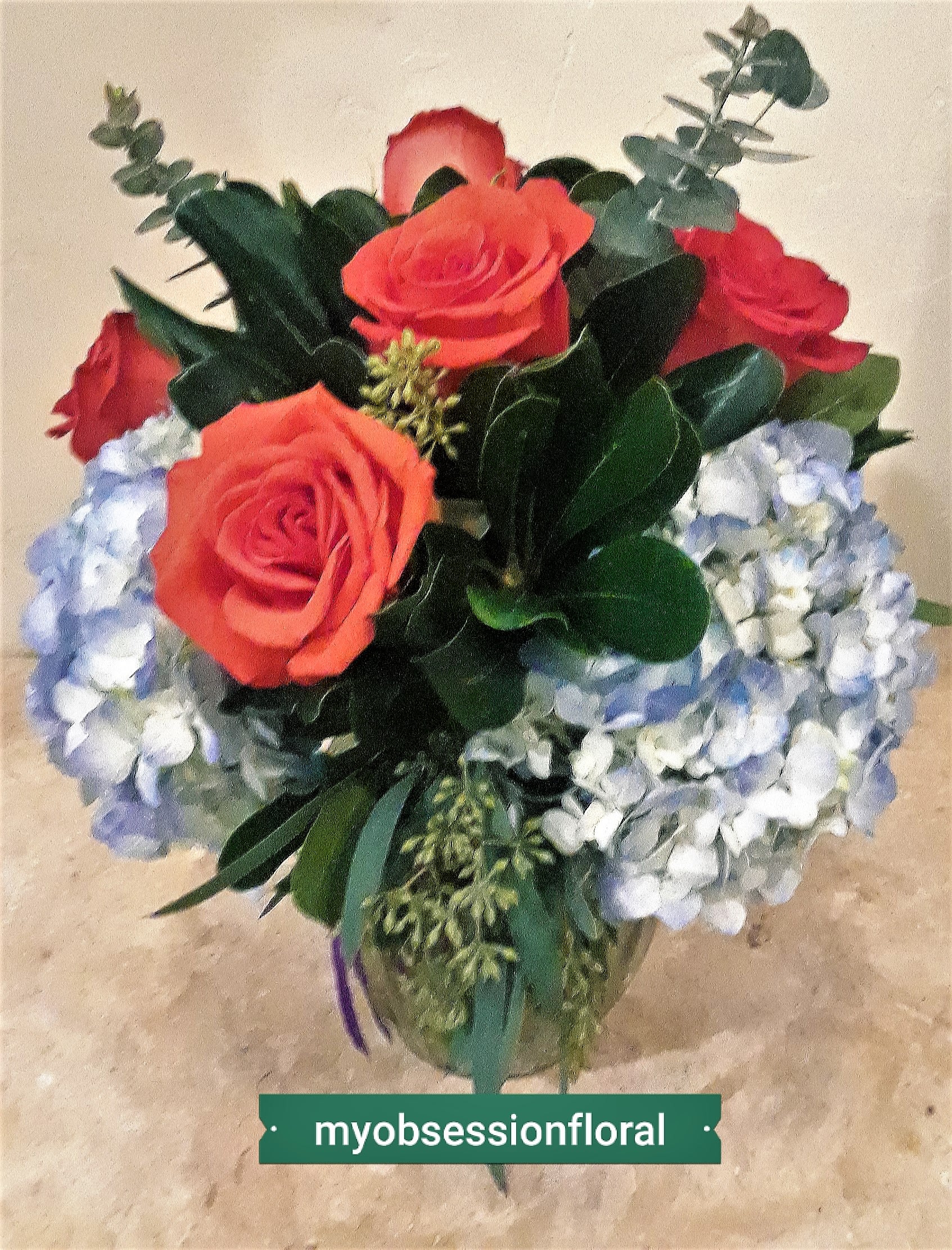 Bouquet of coral roses and pale blue hydrangeas in a glass vase