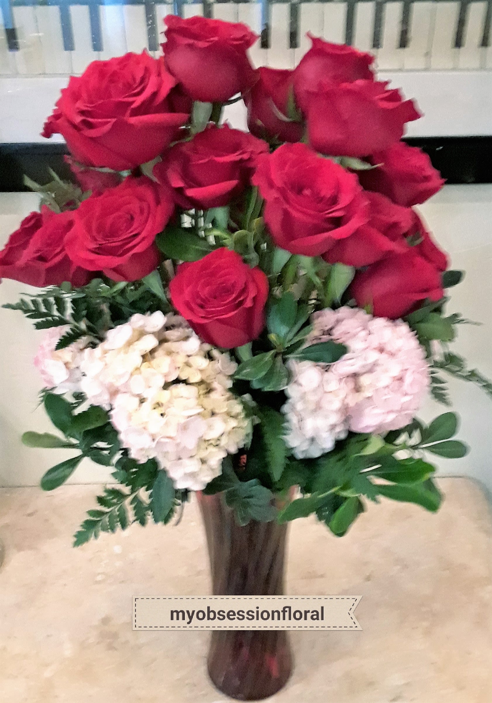 Bouquet of red roses and pale hydrangeas in a tall vase