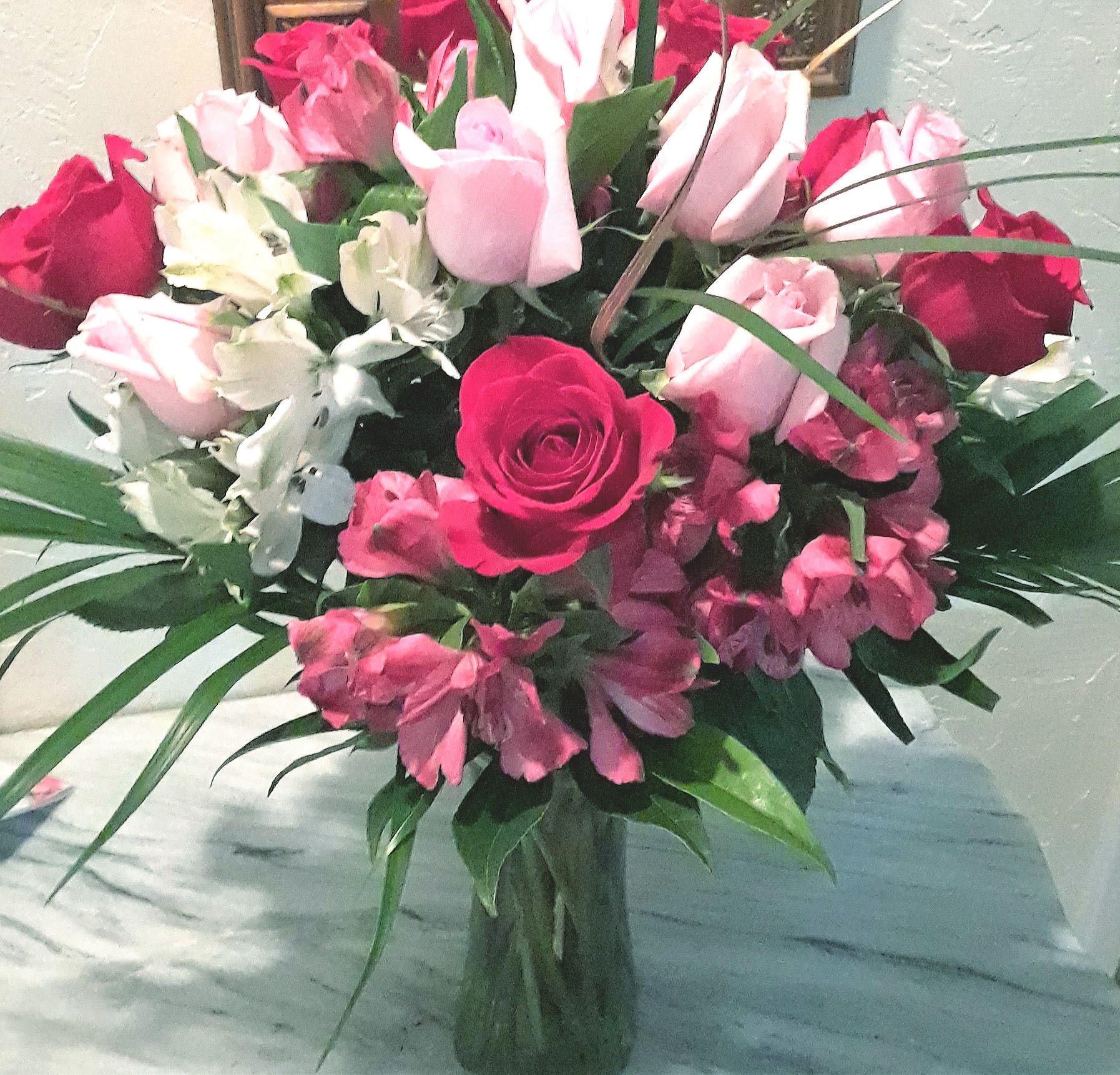 Bouquet of pink and red roses with white flowers in a glass vase
