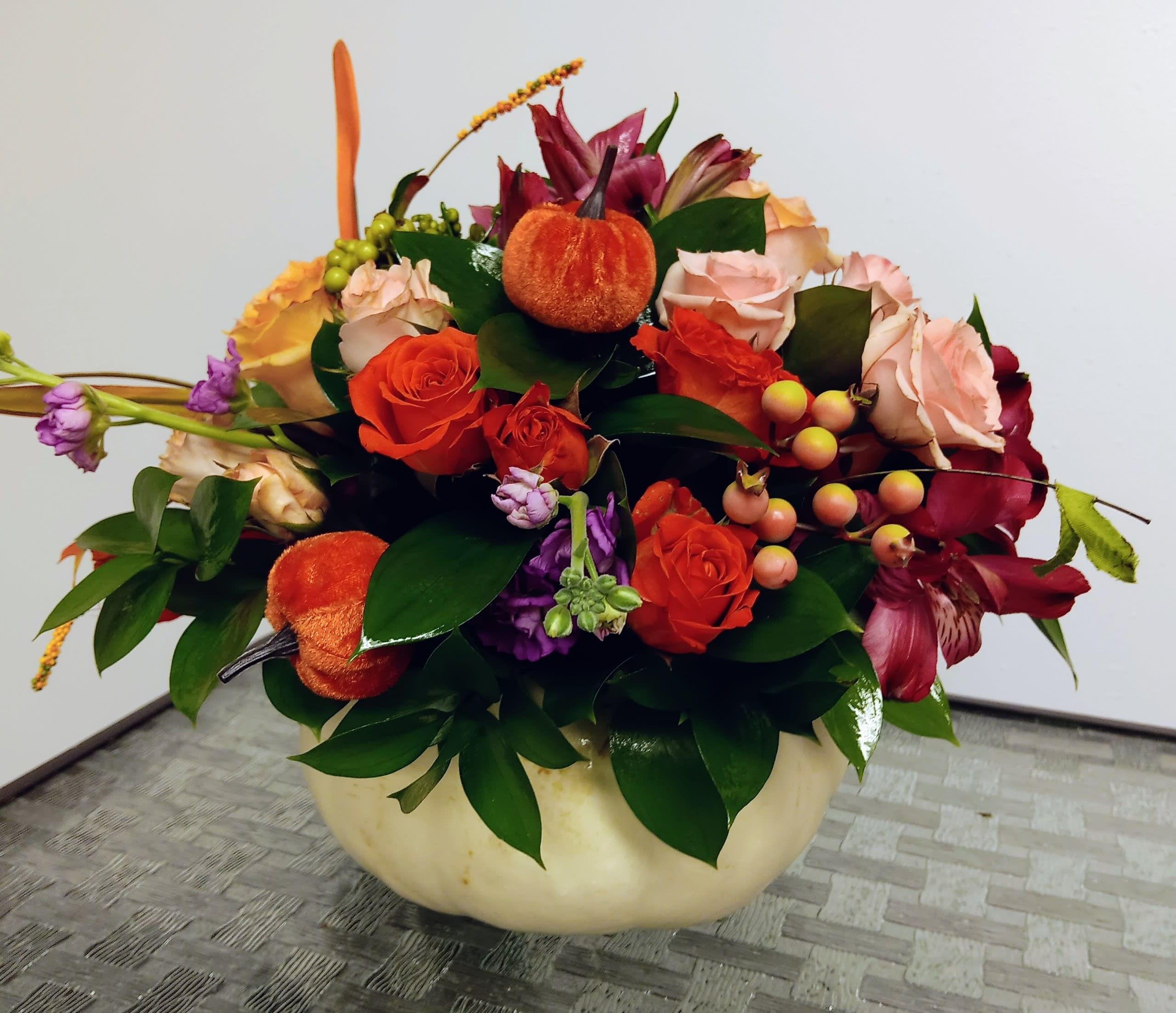 Autumn floral arrangement with roses and lilies in a cream bowl