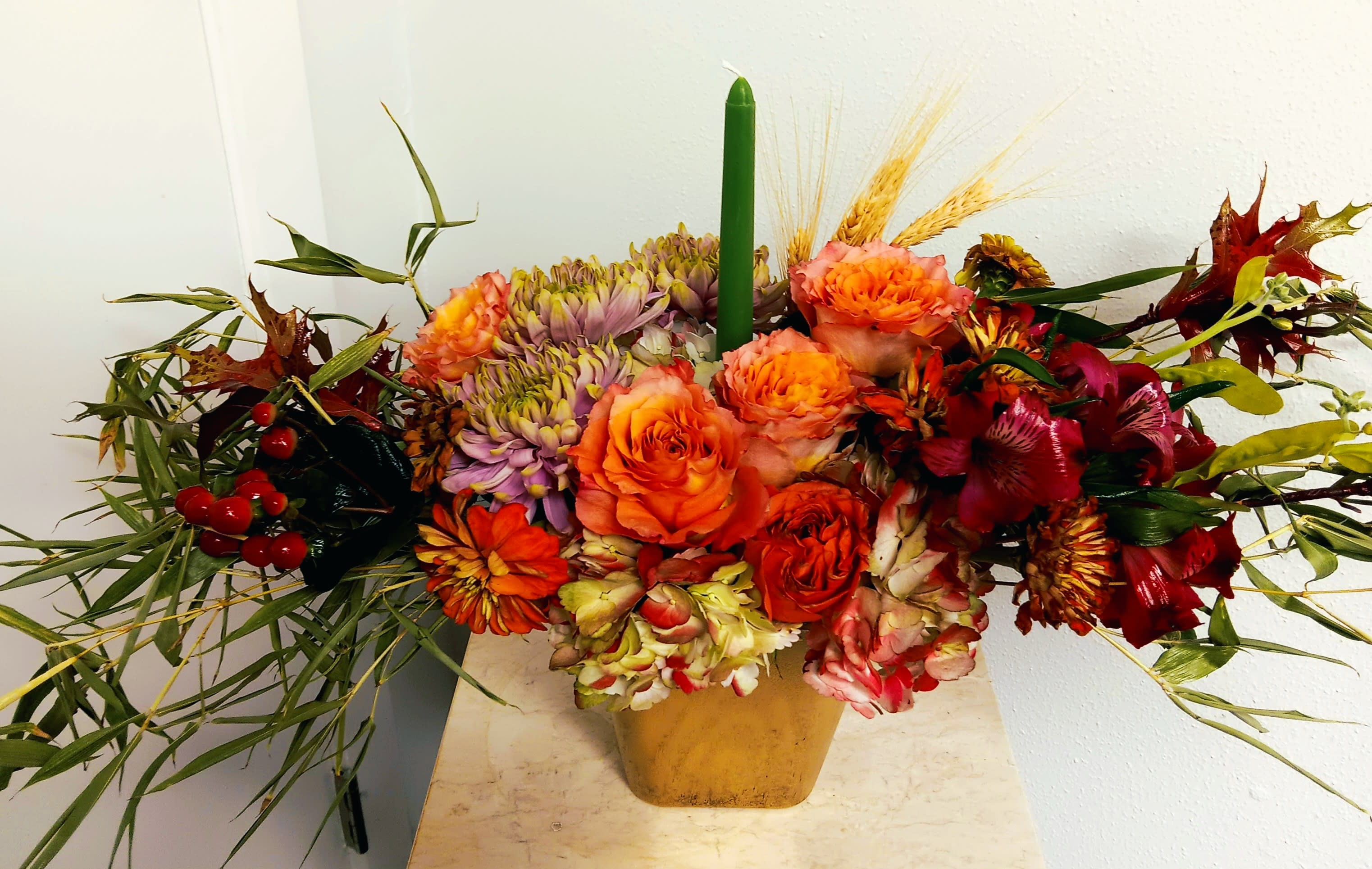 Autumn floral arrangement with orange and red blooms in a gold vase