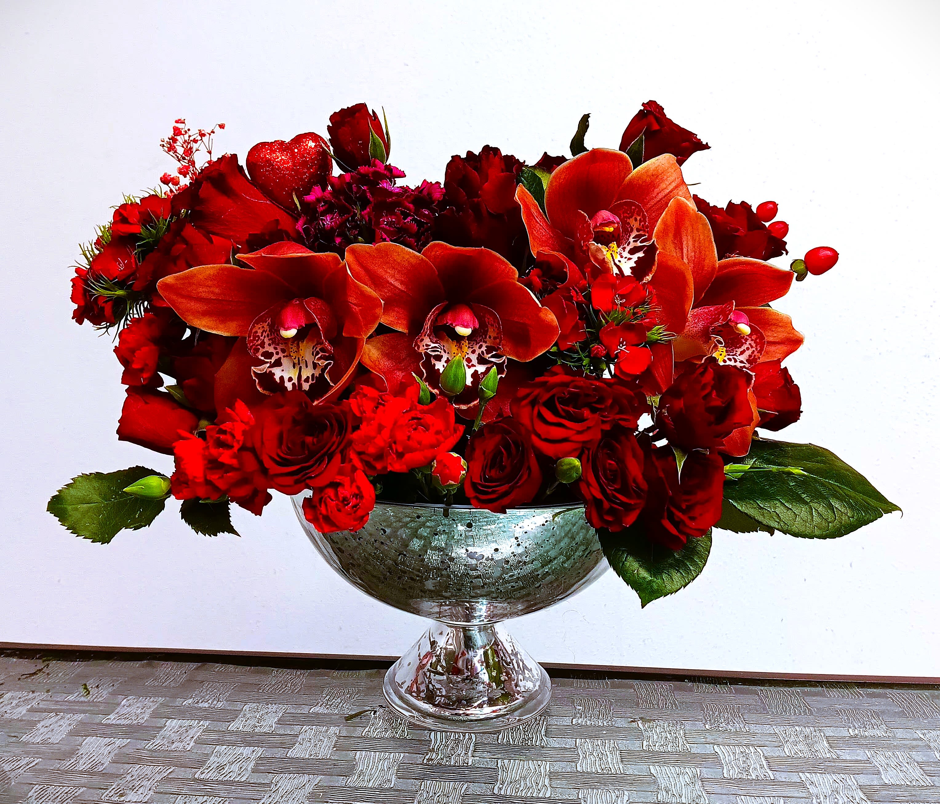 Red floral arrangement in a glass pedestal bowl