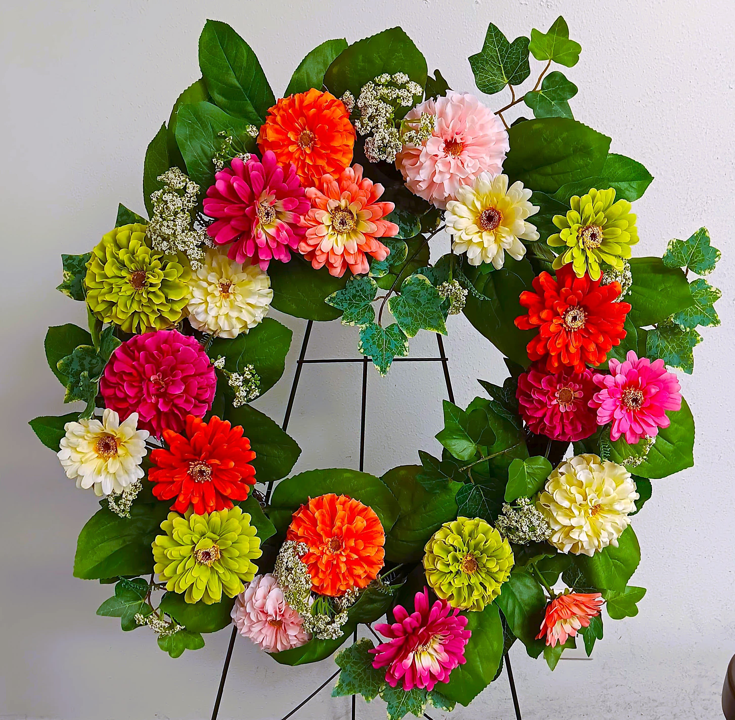 Colorful flower wreath with zinnias on a black stand