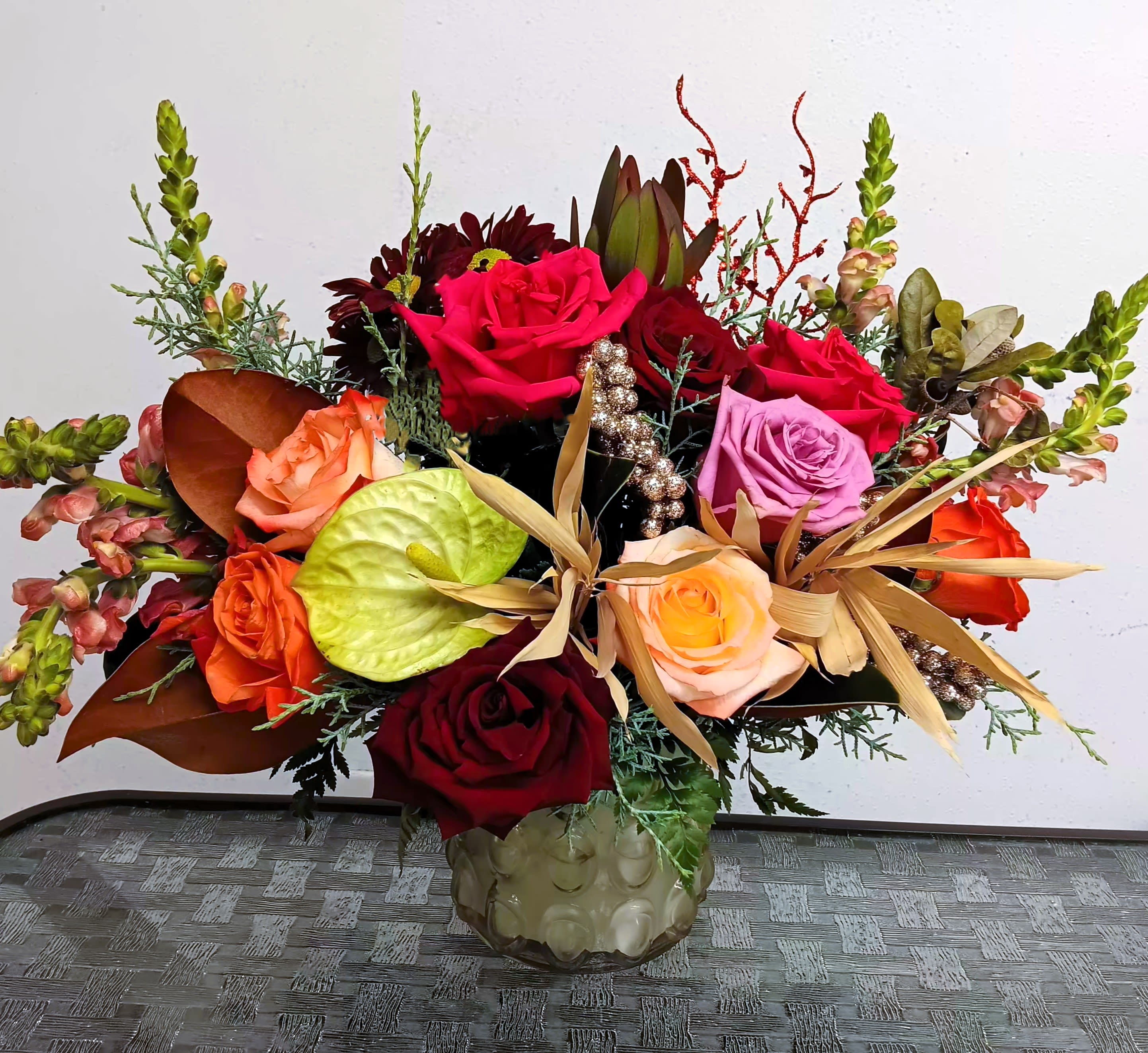 Mixed bouquet of roses and tropical accents in a glass vase