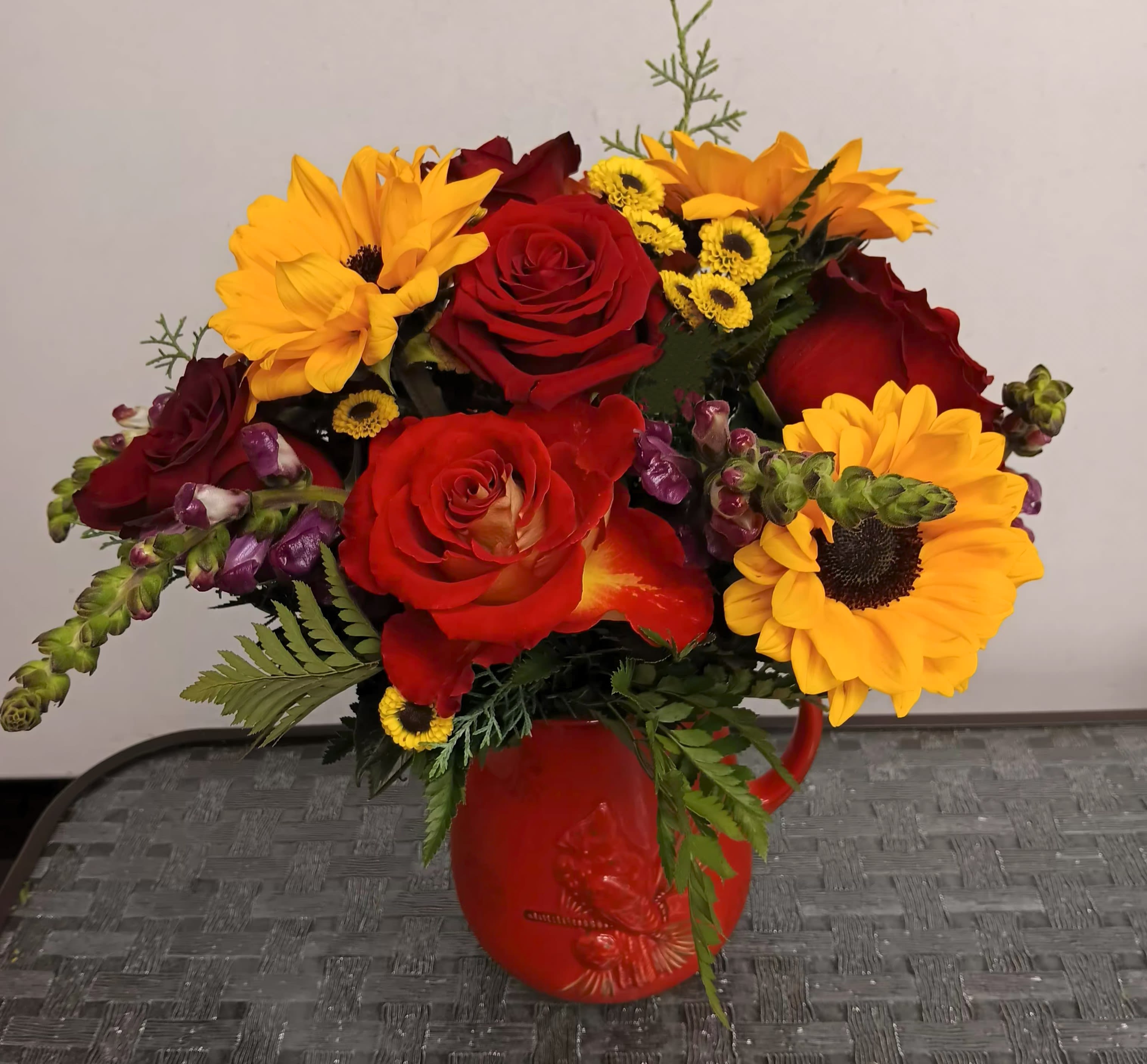 Bouquet of red roses and yellow sunflowers in a red vase