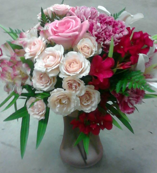 Pink and white rose bouquet in a vase with red accent flowers