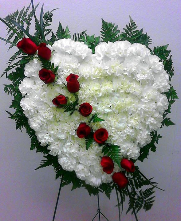 Heart-shaped white floral spray with red roses on a stand