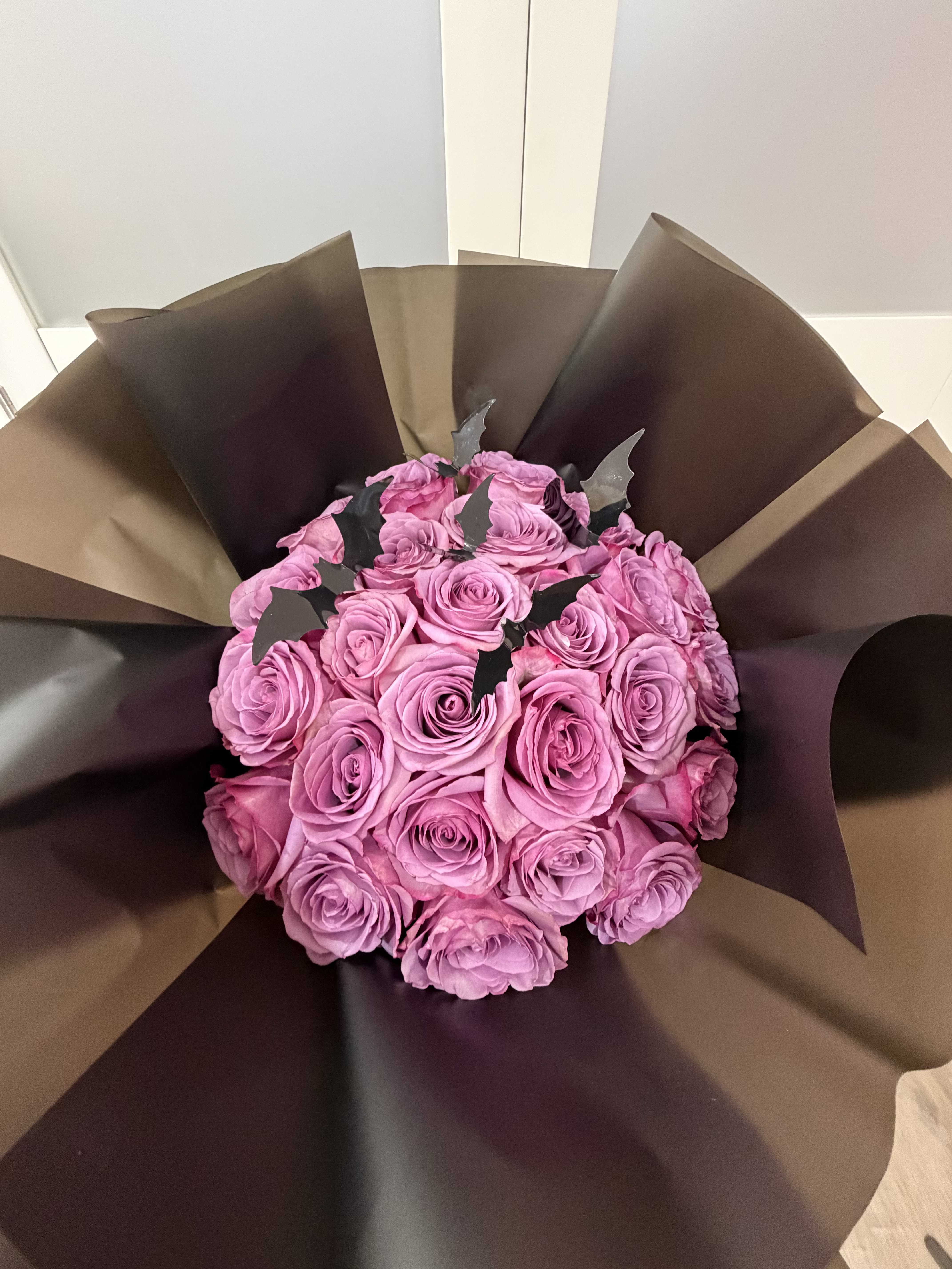 Midnight Bloom Bouquet - A captivating arrangement that blends elegance with a touch of mystery.  Our Midnight Bloom Bouquet features lush lavender roses wrapped in deep, dramatic tones — accented with delicate black bat details for a chic, Halloween-inspired twist.  Perfect for gifting or decorating your space with a statement that's both romantic and bold.  Roses can be customized to any color upon request.  Thoughtfully handcrafted with love, from our hearts to your hands.