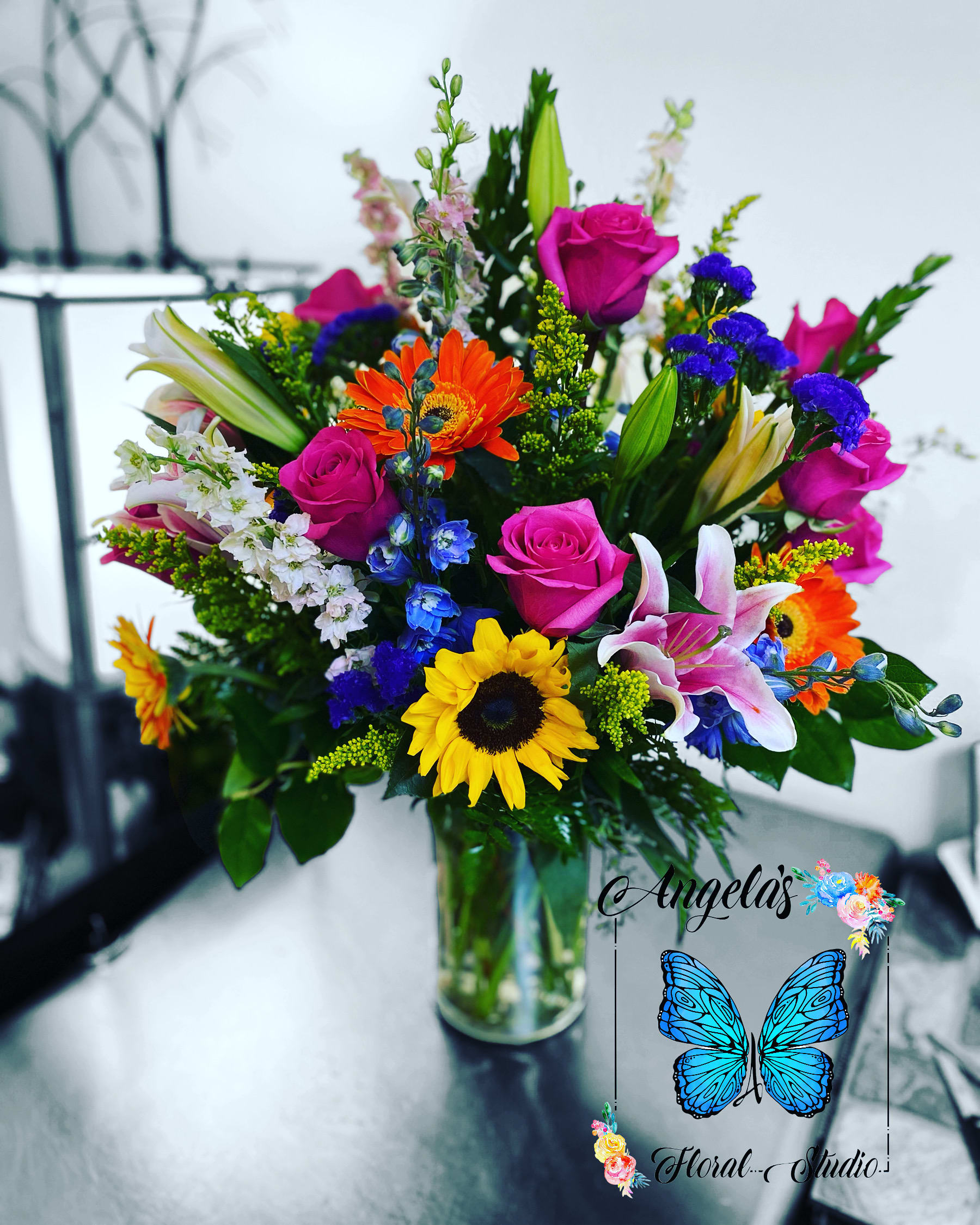 Mixed bouquet of roses, lilies, and sunflowers in a glass vase