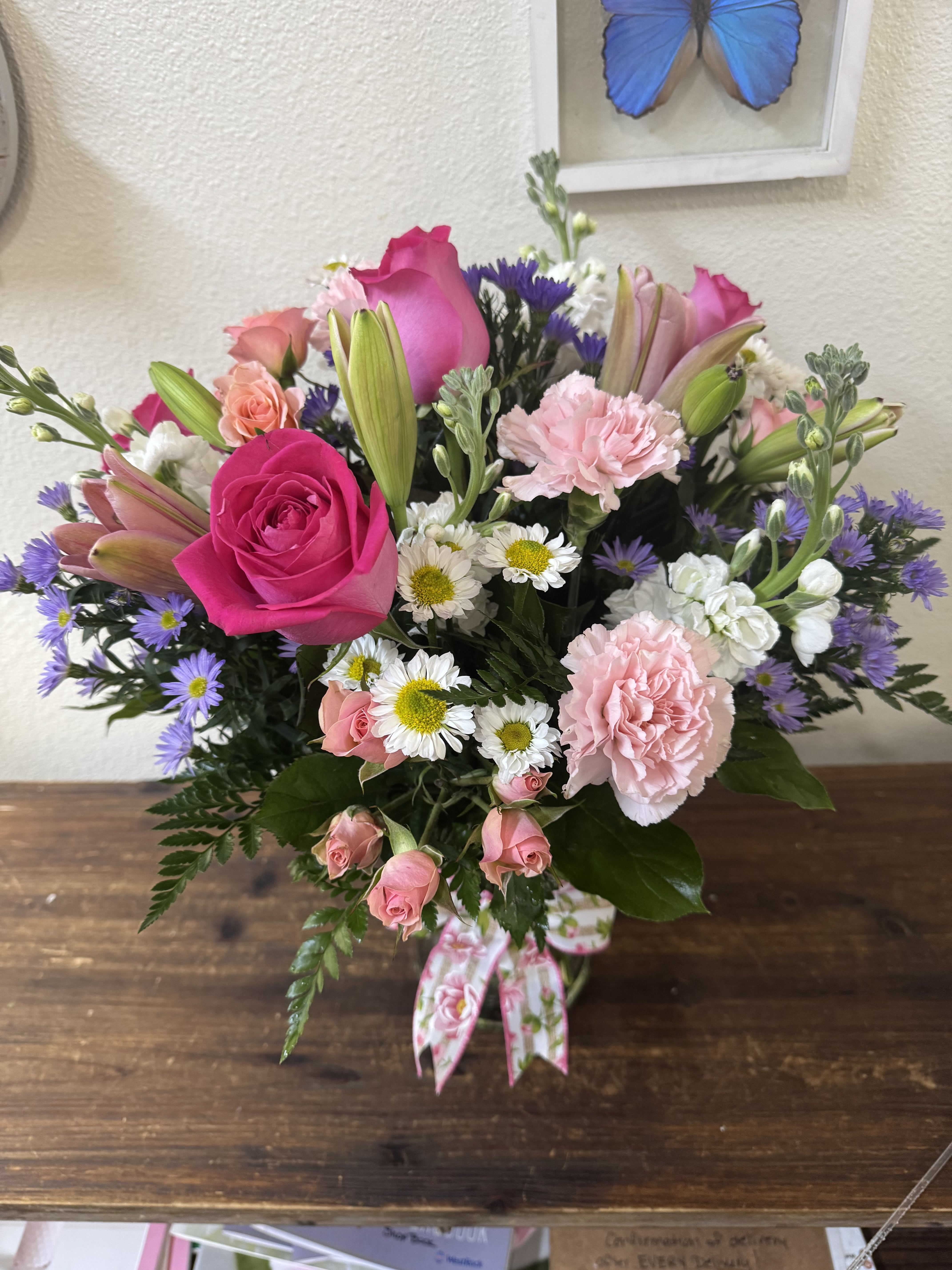 Pink and purple mixed bouquet with roses, lilies, carnations, and daisies