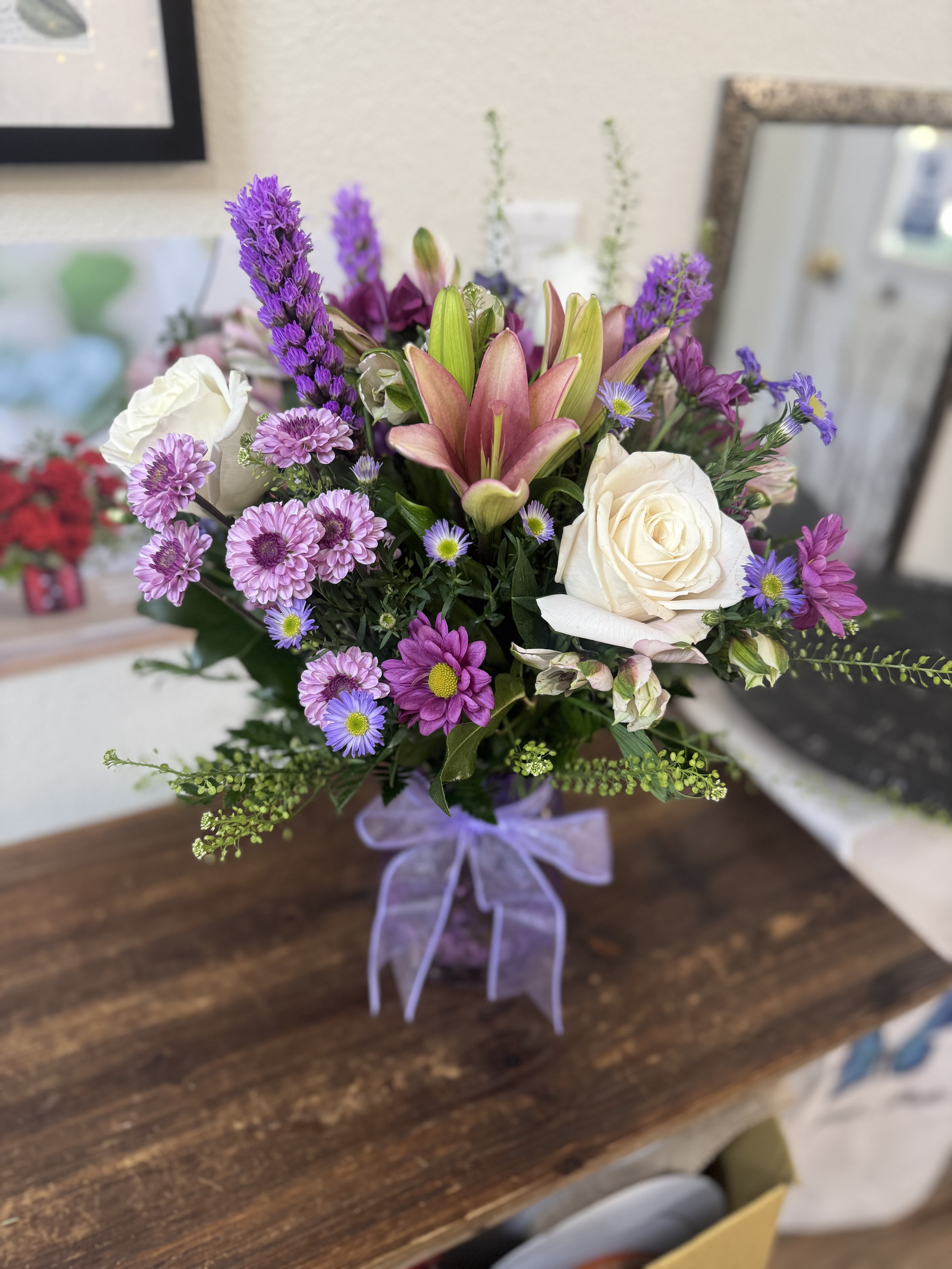 Bouquet of pink lilies, white roses, and purple daisies in a vase