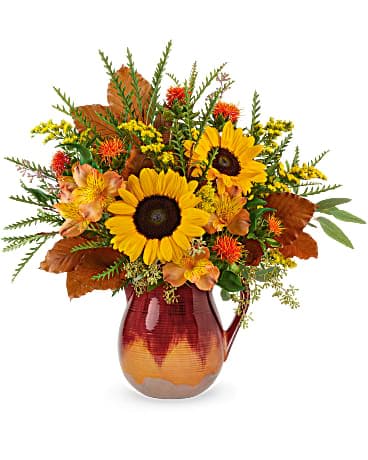 Teleflora's Alluring Ombre Bouquet - The essence of autumnal allure, this beautiful fall bouquet is presented in a food-safe, hand-glazed stoneware pitcher with gorgeous ombre finish. This bouquet features orange alstroemeria, medium yellow sunflowers, orange safflower, solidago, brown copper beech, seeded eucalyptus and grevillea. Delivered in an Autumn Glaze pitcher.