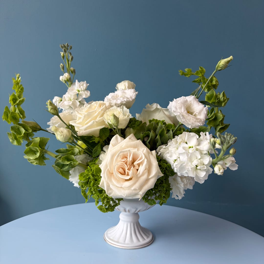 White and cream floral arrangement in a white pedestal vase