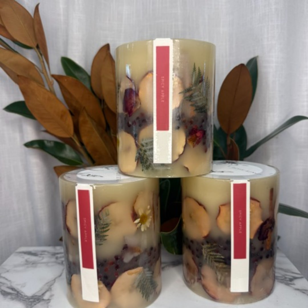 Three decorative pillar candles with dried petals and leaves