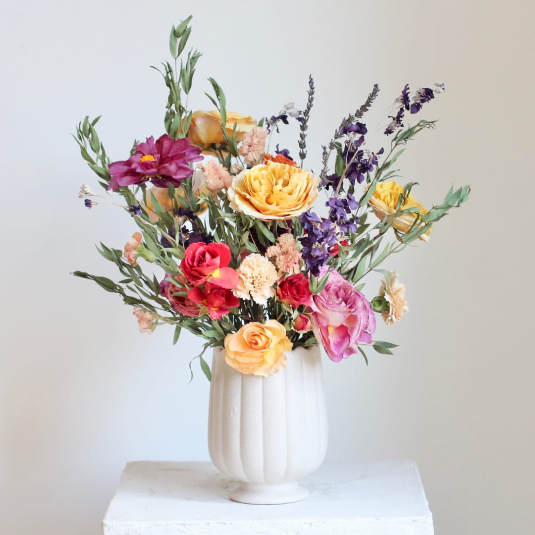 Mixed bouquet of colorful flowers in a white vase