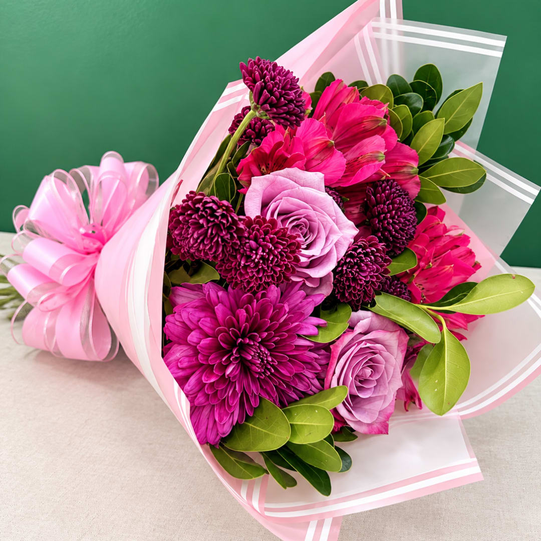 Pink and purple bouquet wrapped in clear and pink paper with a ribbon bow