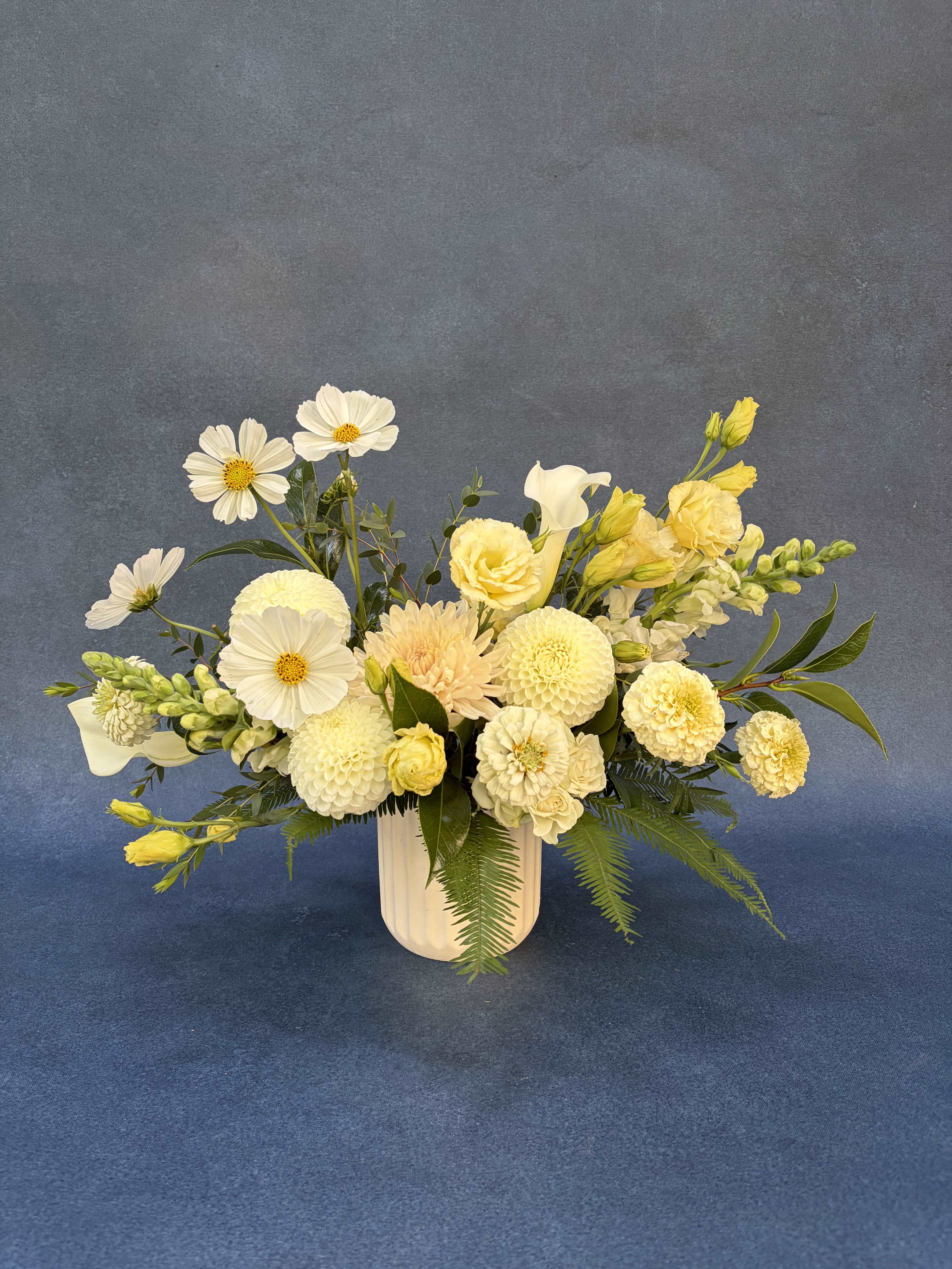 Cream and yellow floral arrangement in a white vase