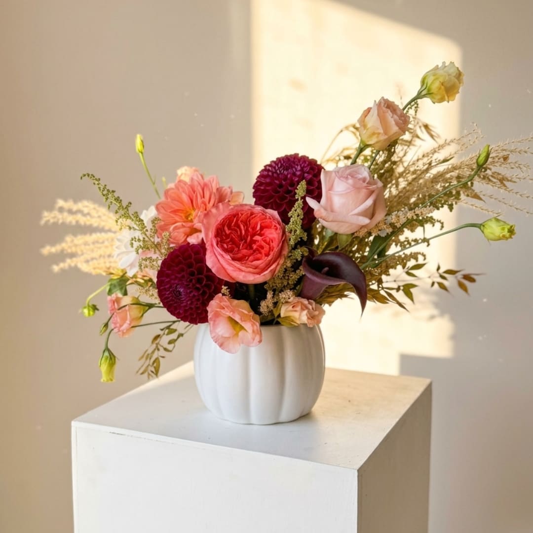 Mixed pink and burgundy flowers arranged in a white vase