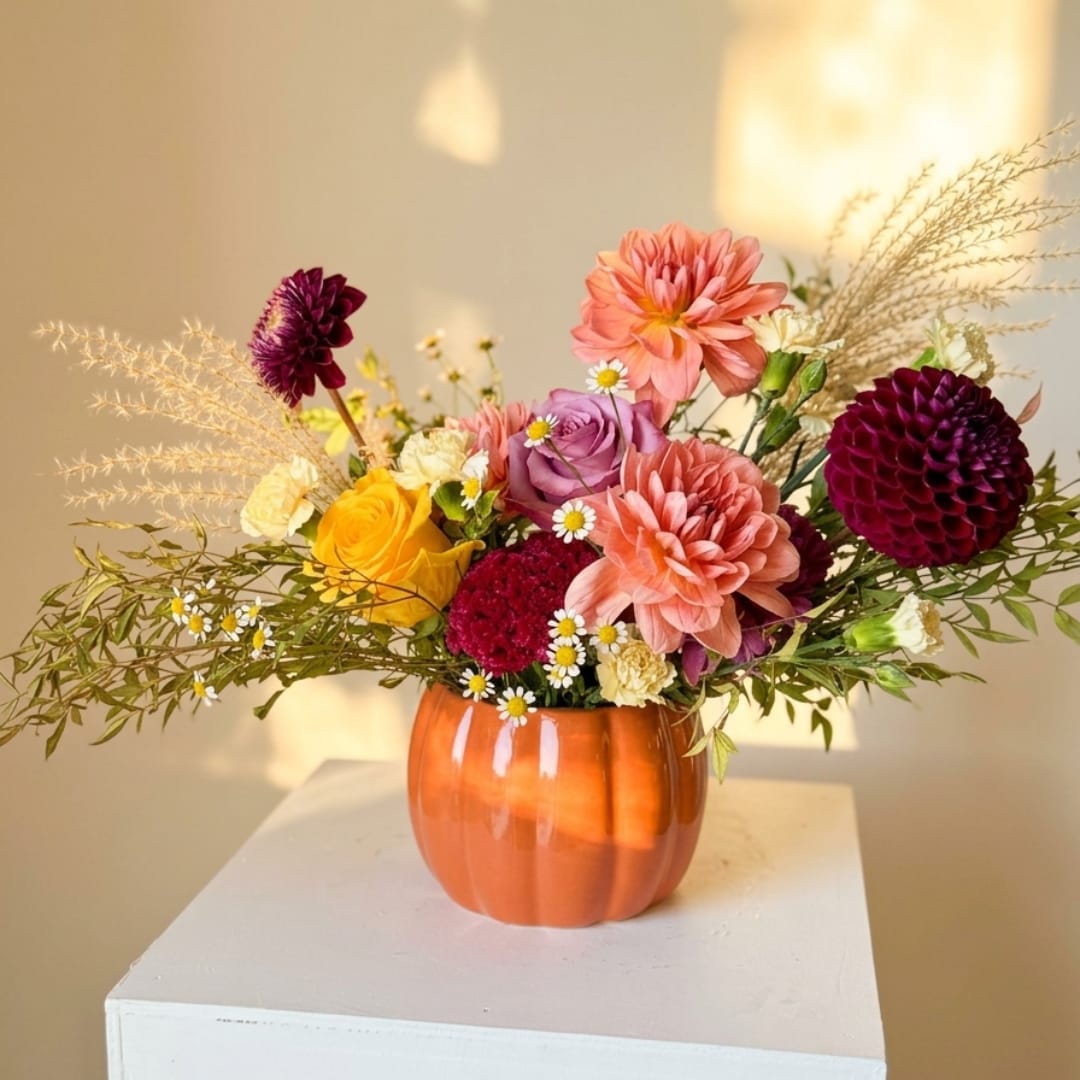 Mixed bouquet in an orange vase with pink, purple, and yellow flowers