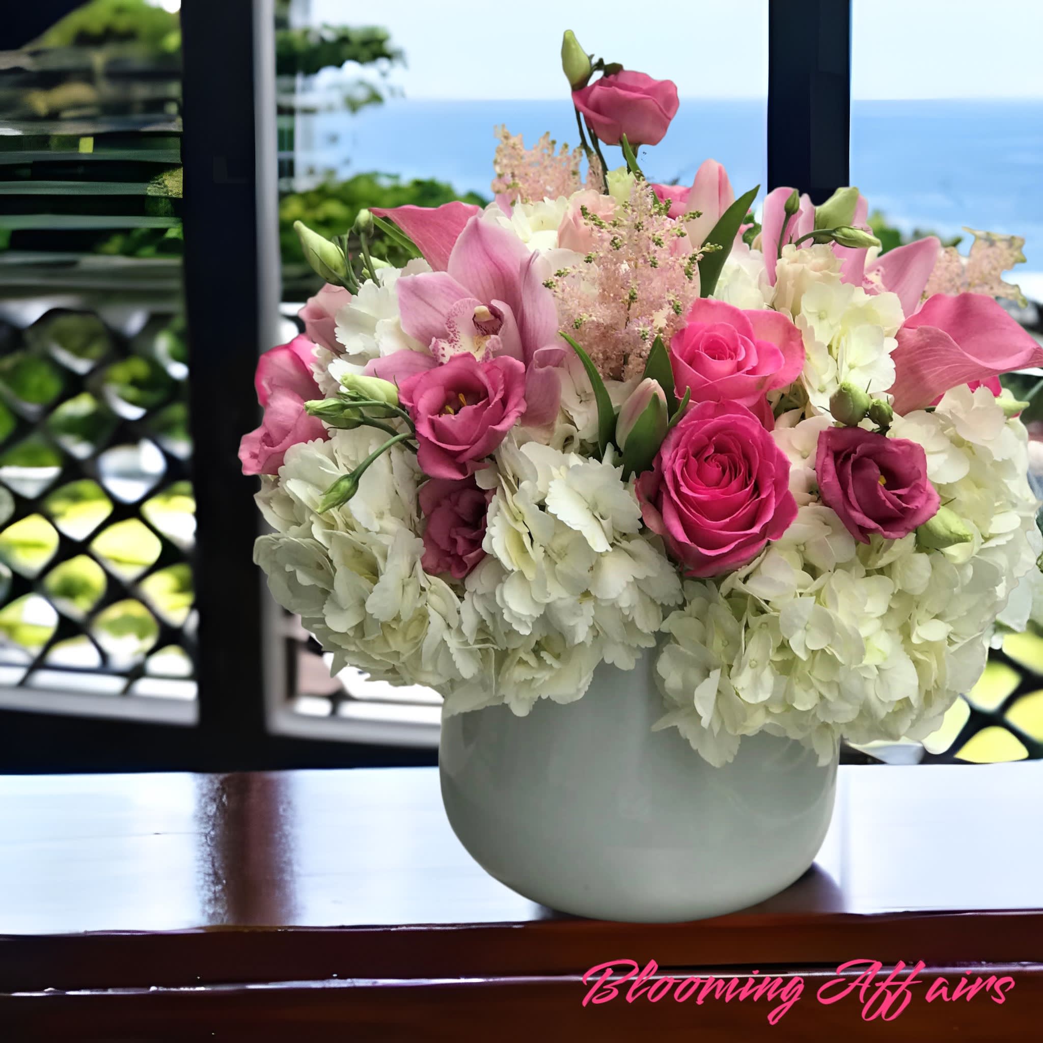Pink roses and lilies arranged in a white vase