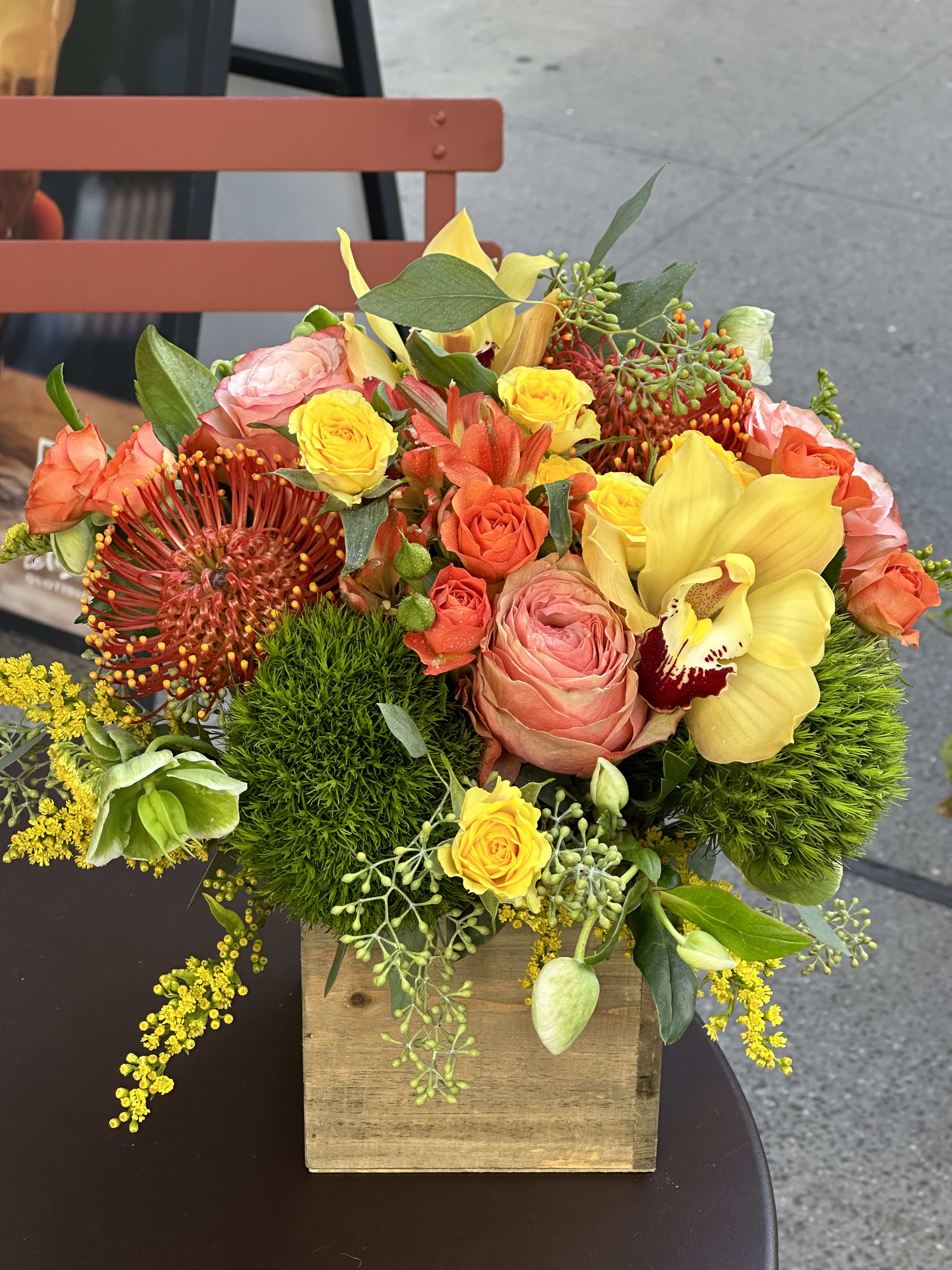 Colorful floral arrangement in a wooden box with roses and orchids