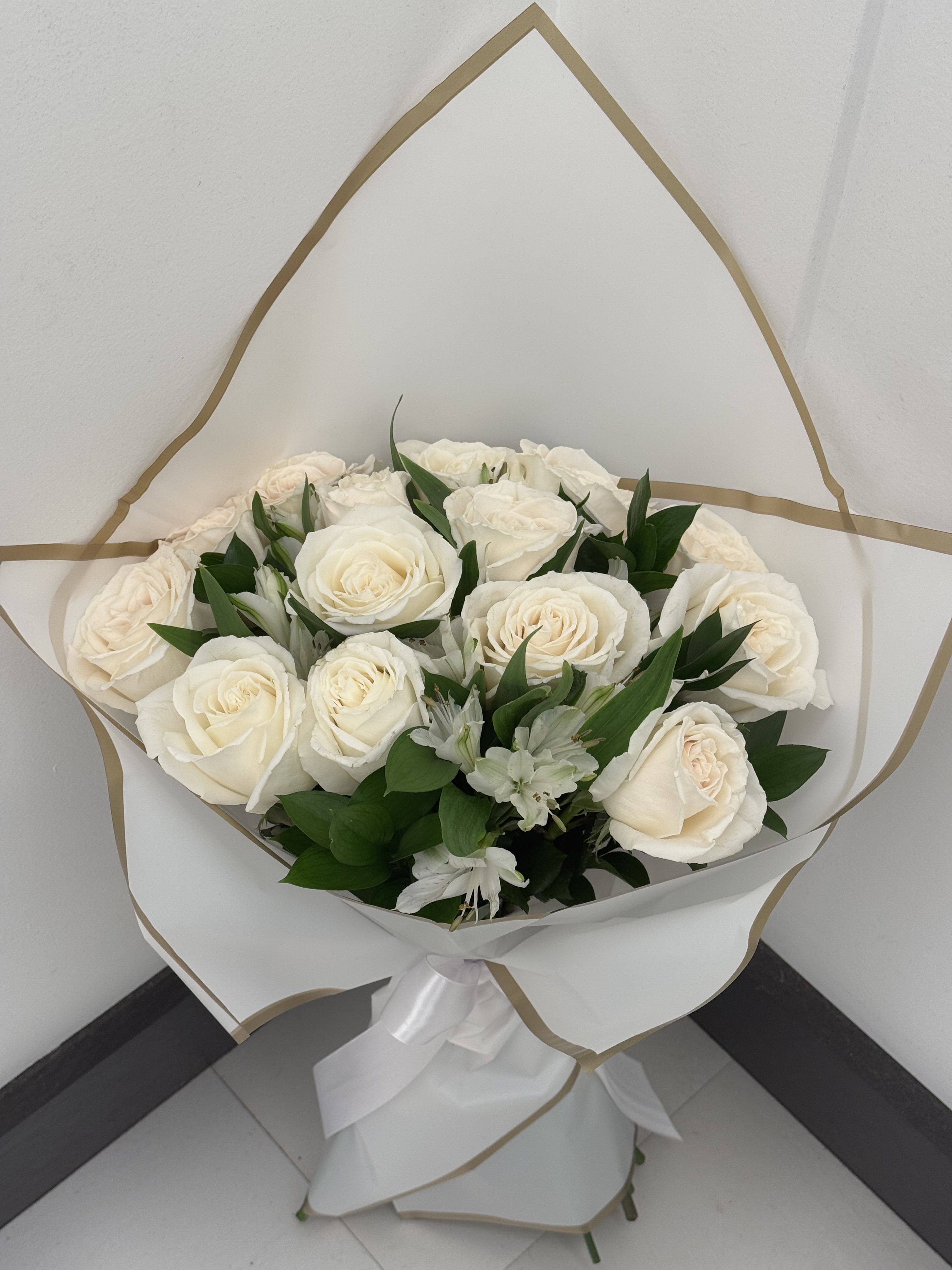 Bouquet of white roses with small white filler flowers wrapped in white paper