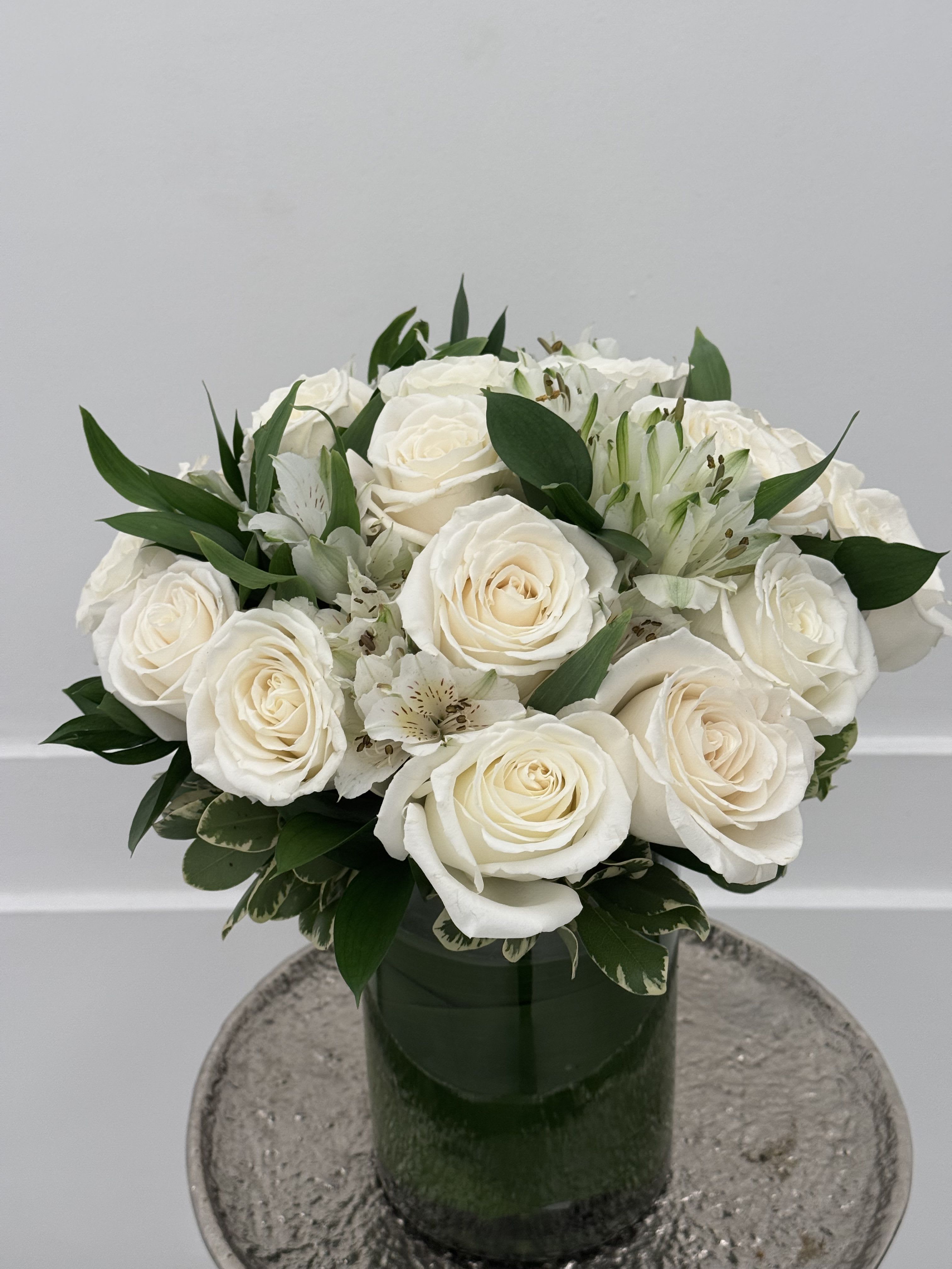 White roses and alstroemeria arranged in a green glass vase