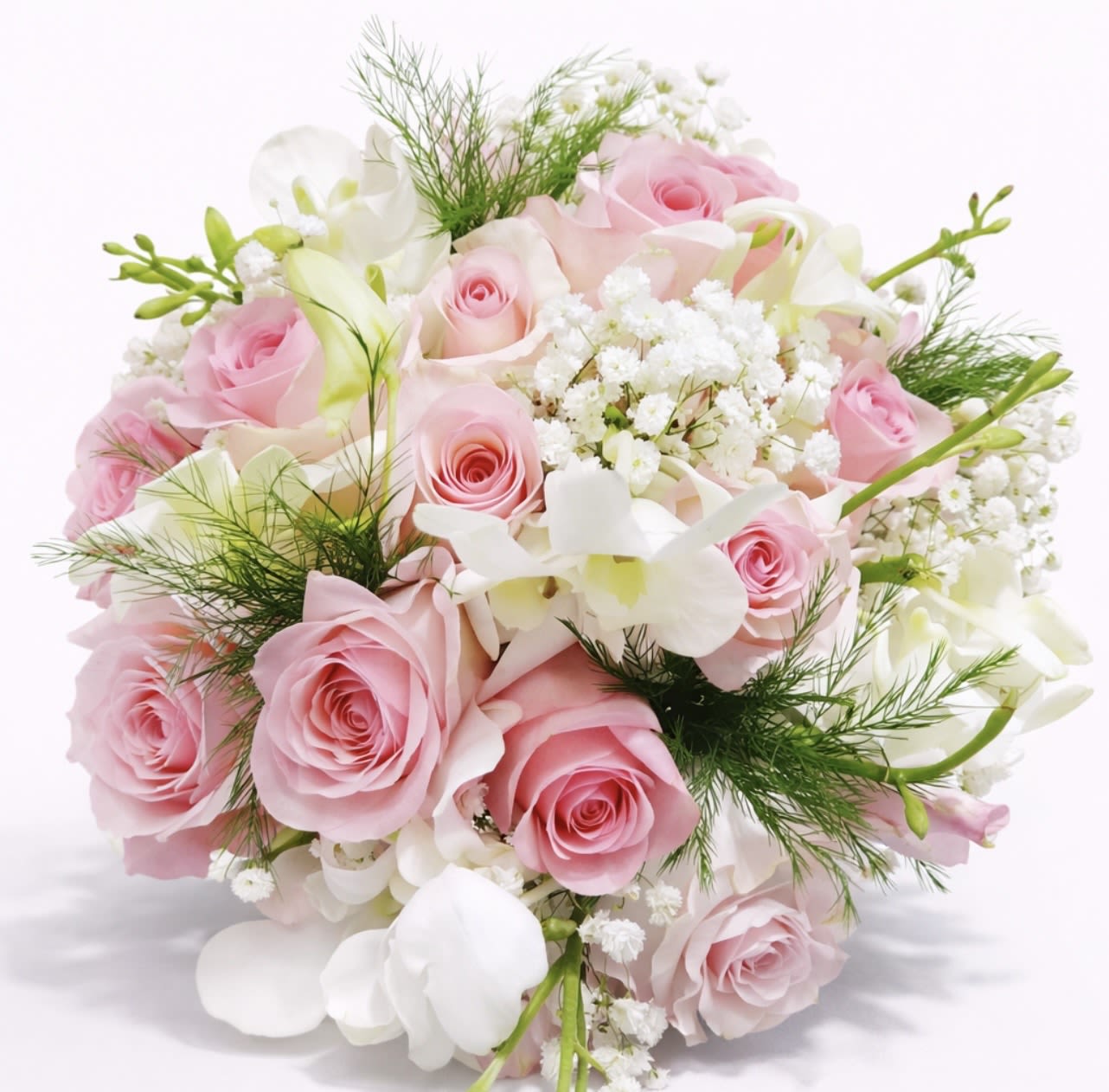 Blush Garden Bride Wedding Bouquet with Pink Roses and Orchids - Soft, romantic and perfectly round-this wedding bouquet gives the bride a gently blushing look that reads timeless and intimate. Blush Garden Bride is a bridal bouquet for weddings that lets her feel truly seen: the soft pink roses and white orchids create a graceful centerpiece she can carry down the aisle or hold for portraits to capture that classic, feminine moment.  A compact, hand-tied design of pink roses paired with white orchids, baby's breath and freesia/stock accents, the arrangement is threaded with wispy green foliage for a light, garden-fresh texture. Stems are neatly wrapped in white bouquet wrap ribbon and shown standing in a clear glass cylinder vase with water for delivery - the clean silhouette keeps attention on the pastel palette of pink and white while the subtle greenery adds contrast.  Ideal for brides, bridesmaids, anniversaries or vow renewals, this bouquet reads as romantic without feeling fussy; she'll feel cherished and radiant holding it. Available in a standard size suitable for a hand-tied bridal carry, easy-care instructions are included with every order and Flowers for Ladies &amp; Events delivers to Newington, CT for wedding-day pickup or local delivery.