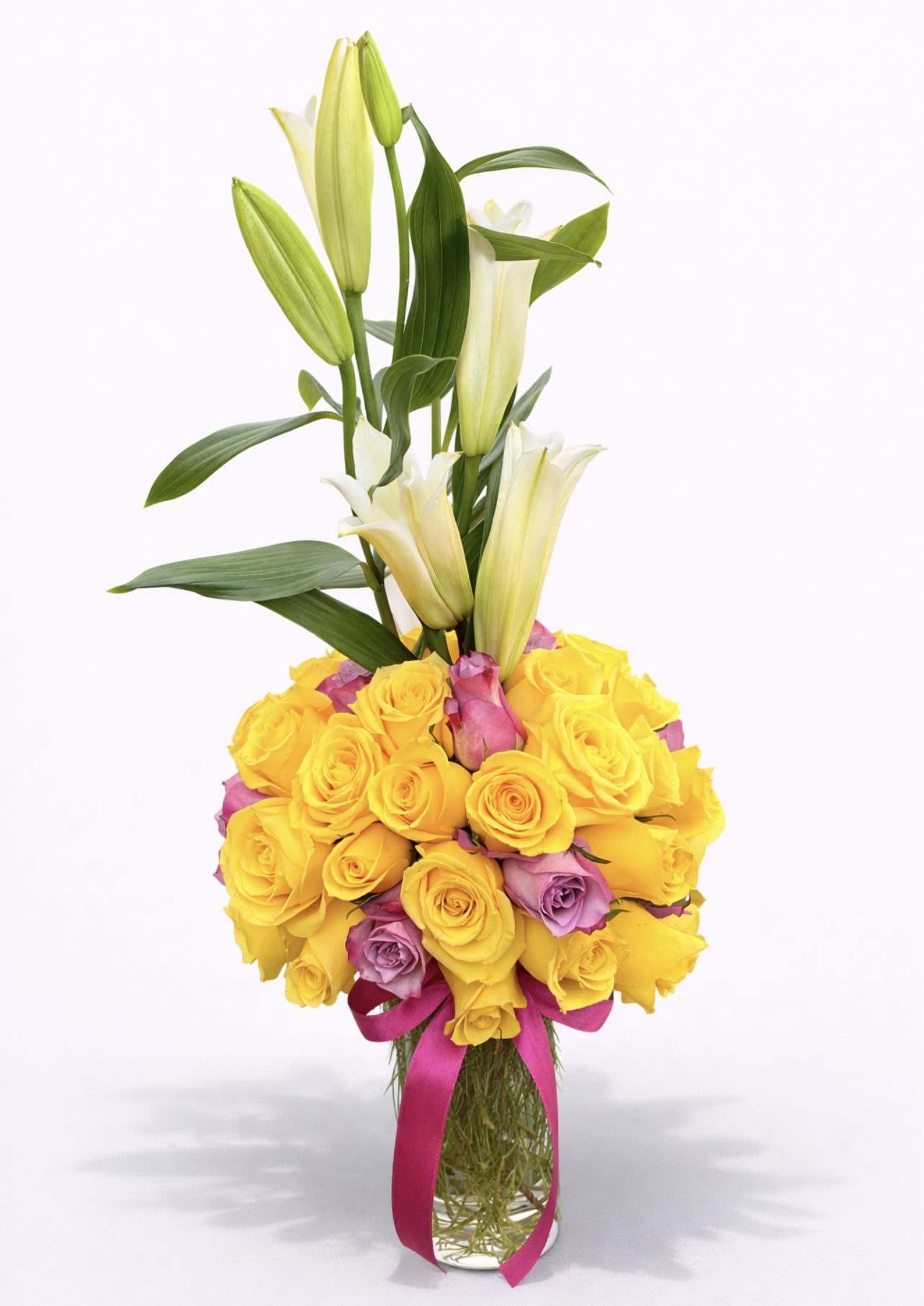 Yellow and pink roses with white lilies in a clear vase