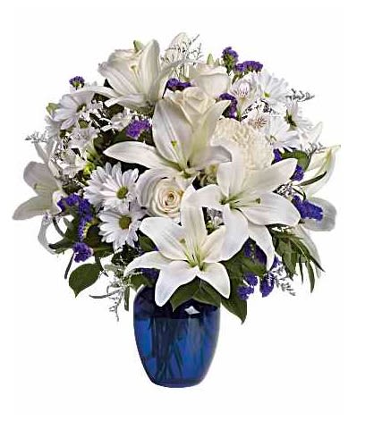 White lilies and daisies in a blue glass vase