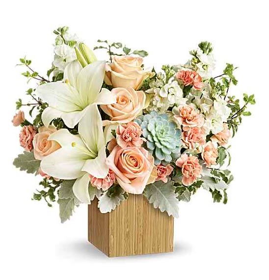 Desert Sunrise Bouquet - Reminiscent of a desert sunrise, this modern mix of peach blooms, white lilies and succulents is a super chic statement in a natural bamboo cube. Peach roses, white asiatic lilies, peach miniature carnations, and white stock are accented with pitta negra, dusty miller, and a green echeveria succulent. Delivered in Teleflora's Small Natural Bamboo Cube. Orientation: One-Sided  SUBSTITUTION POLICY: Please note the bouquet pictured reflects our original design.  If the exact flowers or container in this arrangement are not available, our local florists will create a beautiful bouquet with the freshest available flowers.