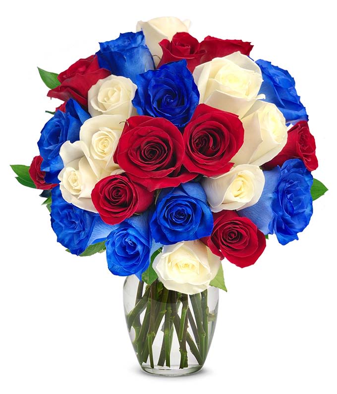 RED, WHITE &amp; BLUE ROSES - A patriotic and elegant arrangement featuring 24 premium long-stem roses in vibrant red, crisp white, and bold blue tones. The roses are artfully gathered in a clear glass vase, creating a full and balanced bouquet that symbolizes celebration, pride, and admiration. The striking color combination makes it perfect for patriotic holidays, military tributes, special events, or heartfelt occasions. Fresh greenery accents complete the design, adding natural texture and contrast to this eye-catching floral display.