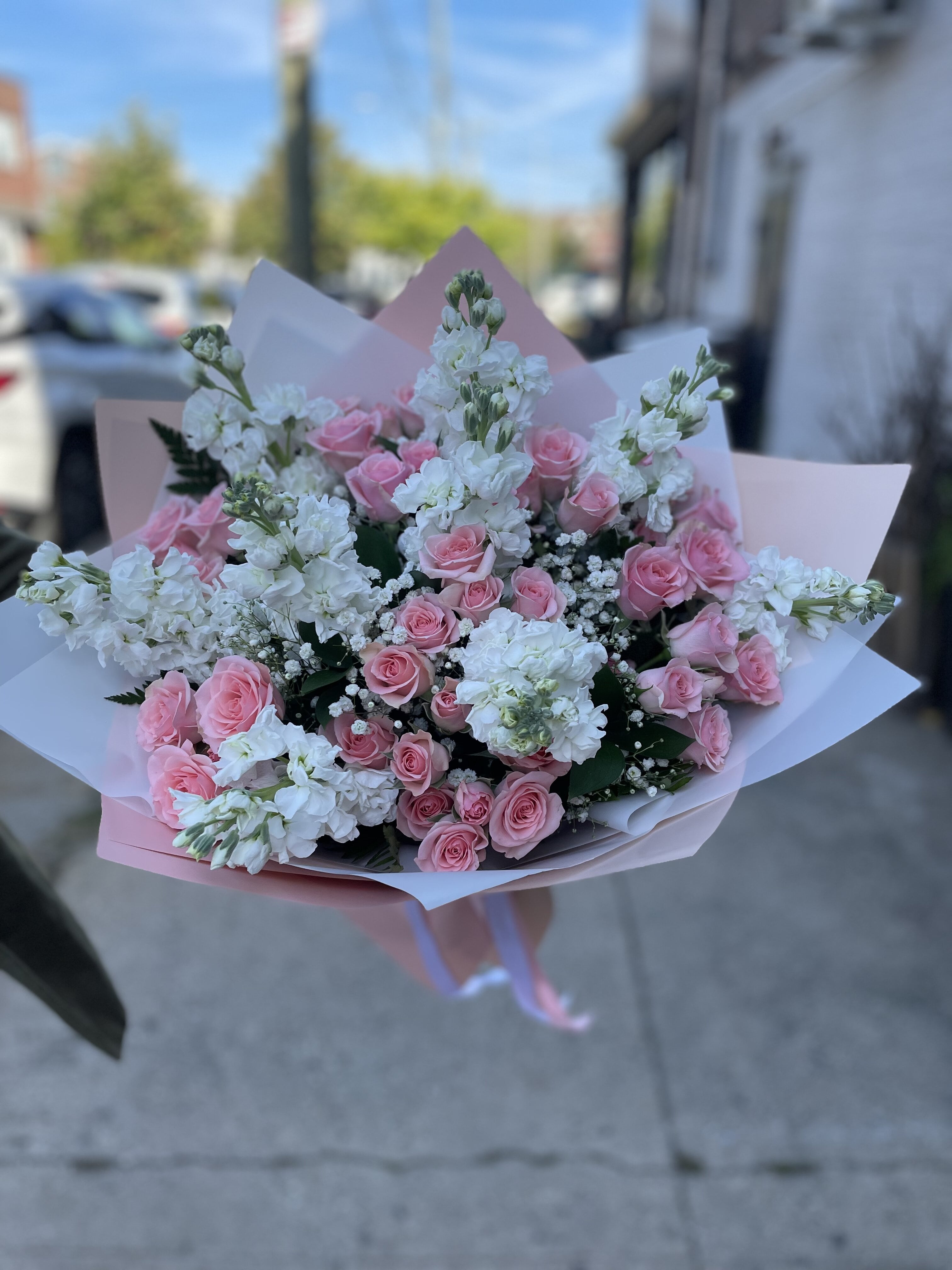 Bouquet of pink roses and white flowers wrapped in pastel paper