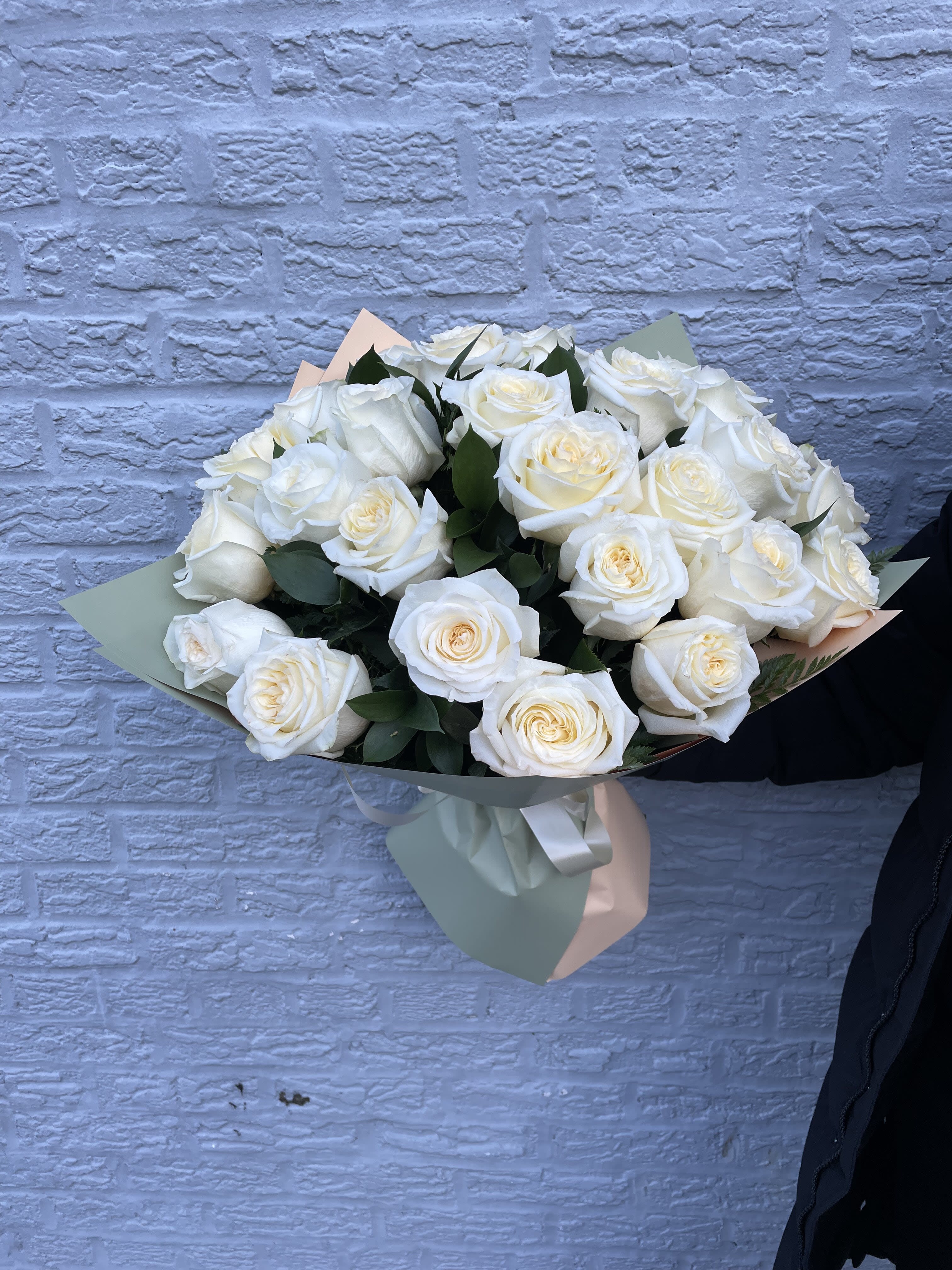 Bouquet of white roses wrapped in pastel paper