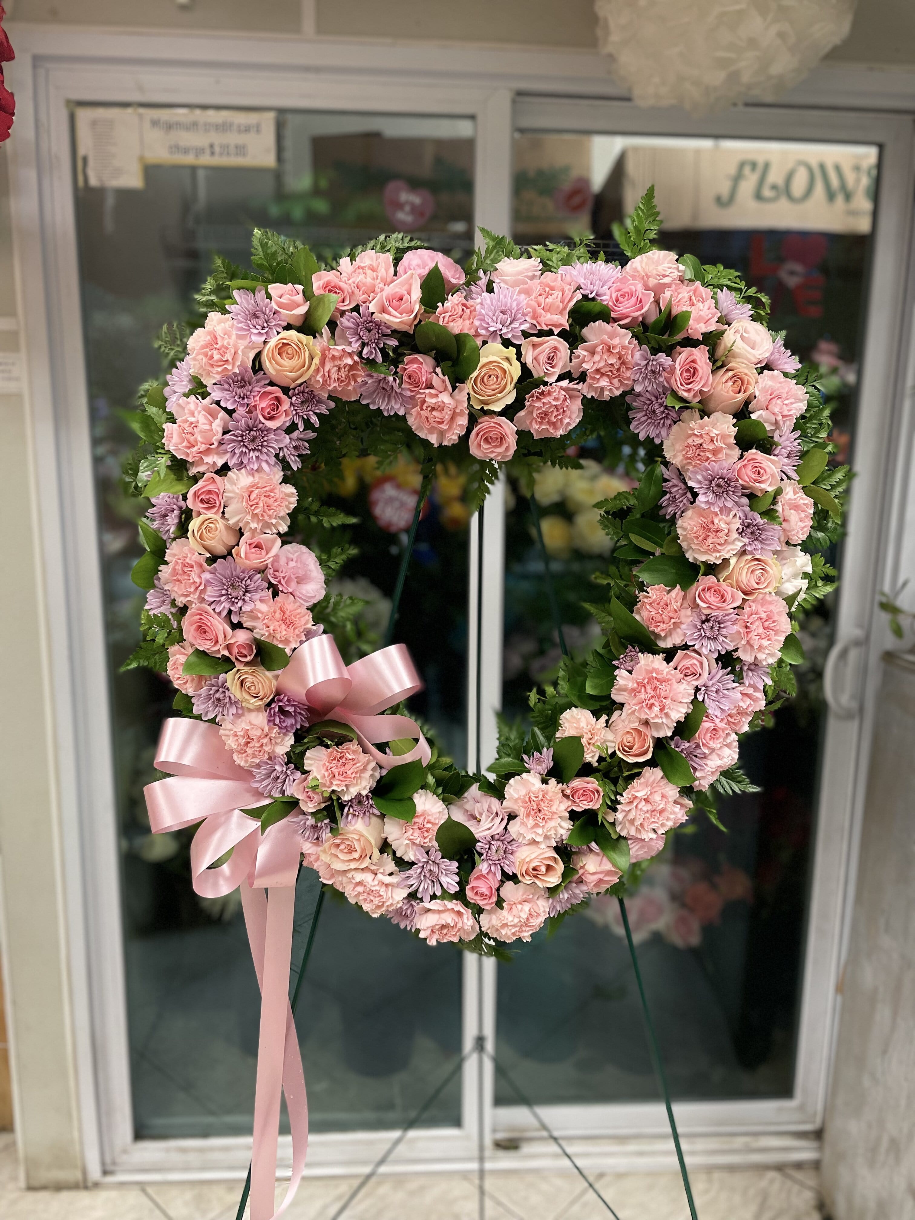 Heart-shaped floral wreath with pink roses, carnations, and lavender mums