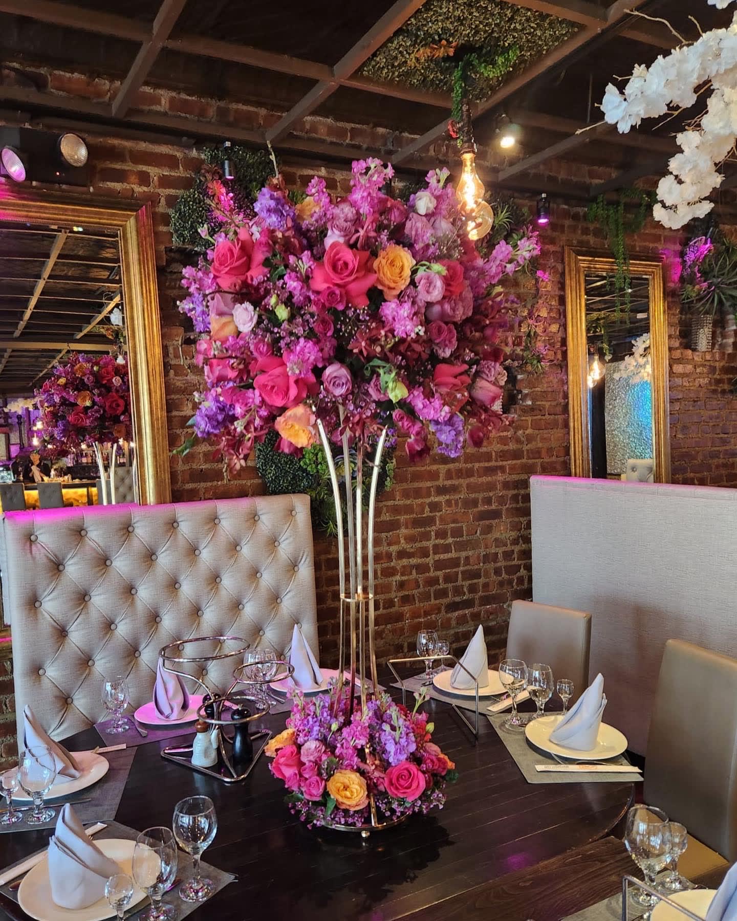 Tall floral centerpiece with pink, purple, and yellow flowers on a dining table