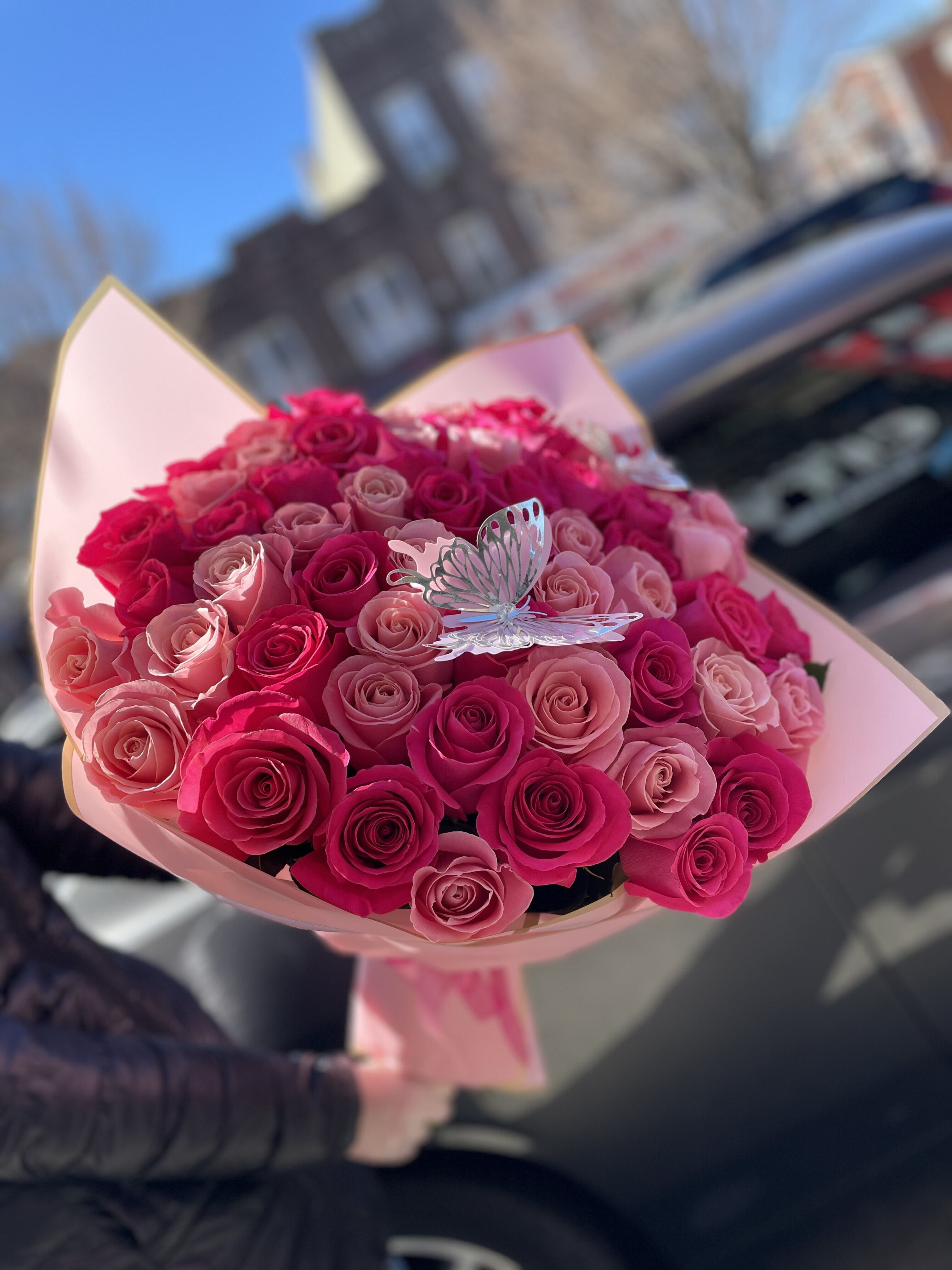 Bouquet of pink and hot pink roses with a butterfly pick