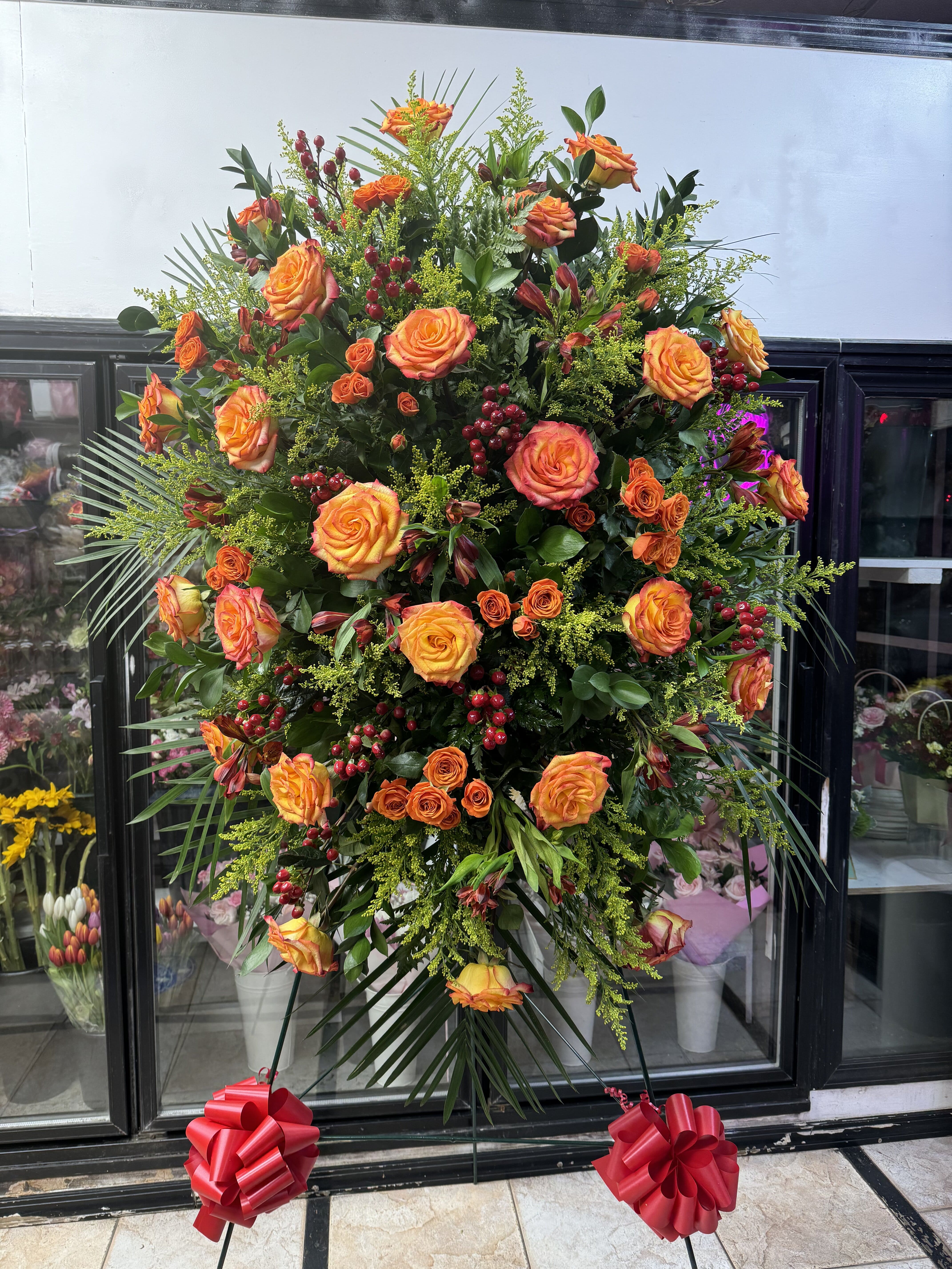 Large standing spray of orange roses with red berries and greenery