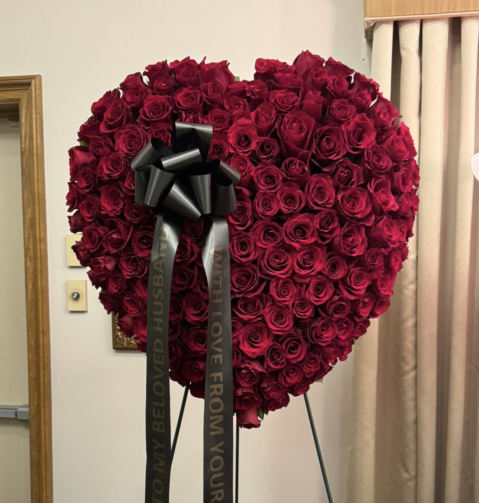 Heart-shaped arrangement of red roses with a black ribbon bow
