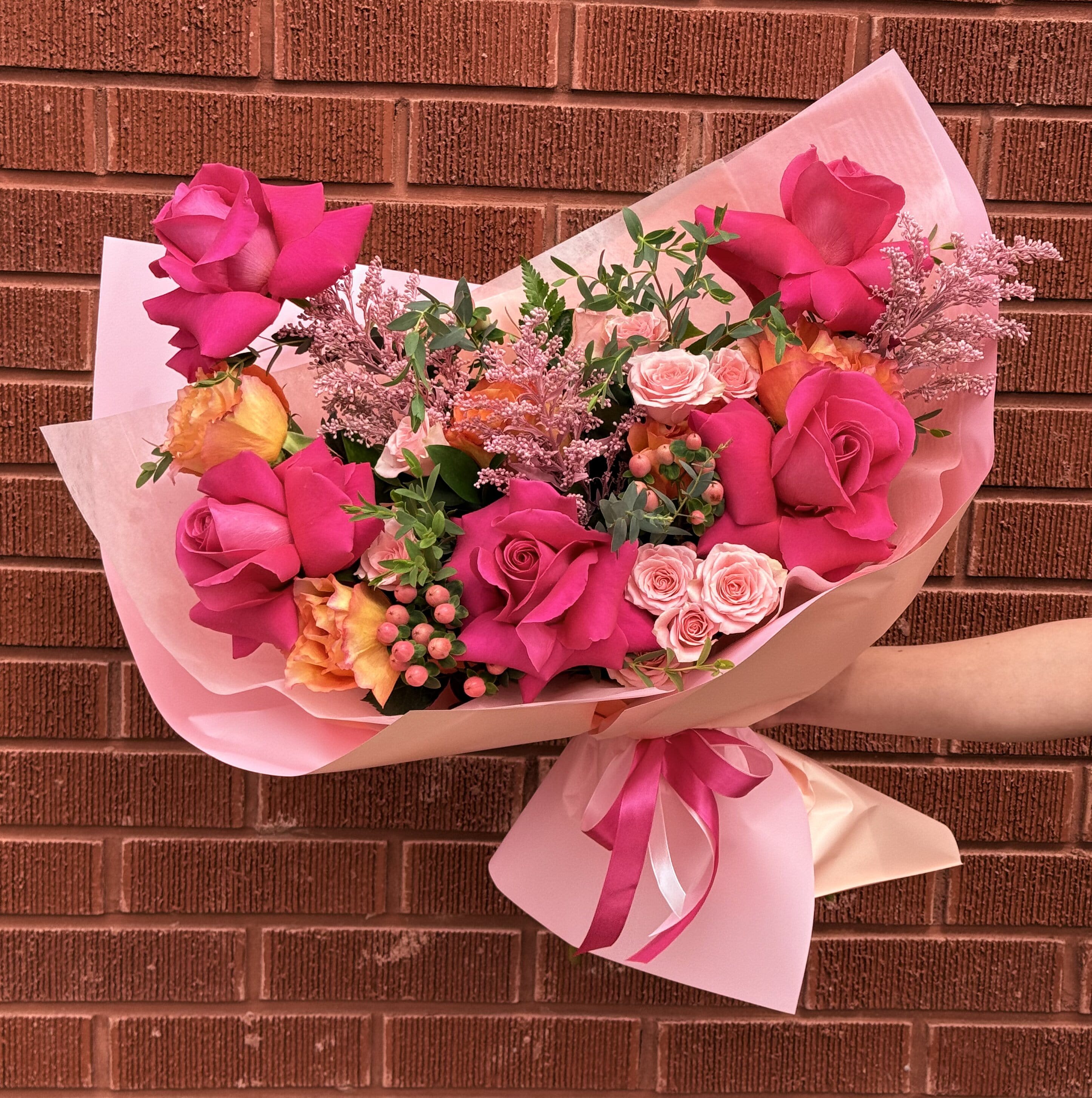 Pink rose bouquet wrapped in pale pink paper with a ribbon
