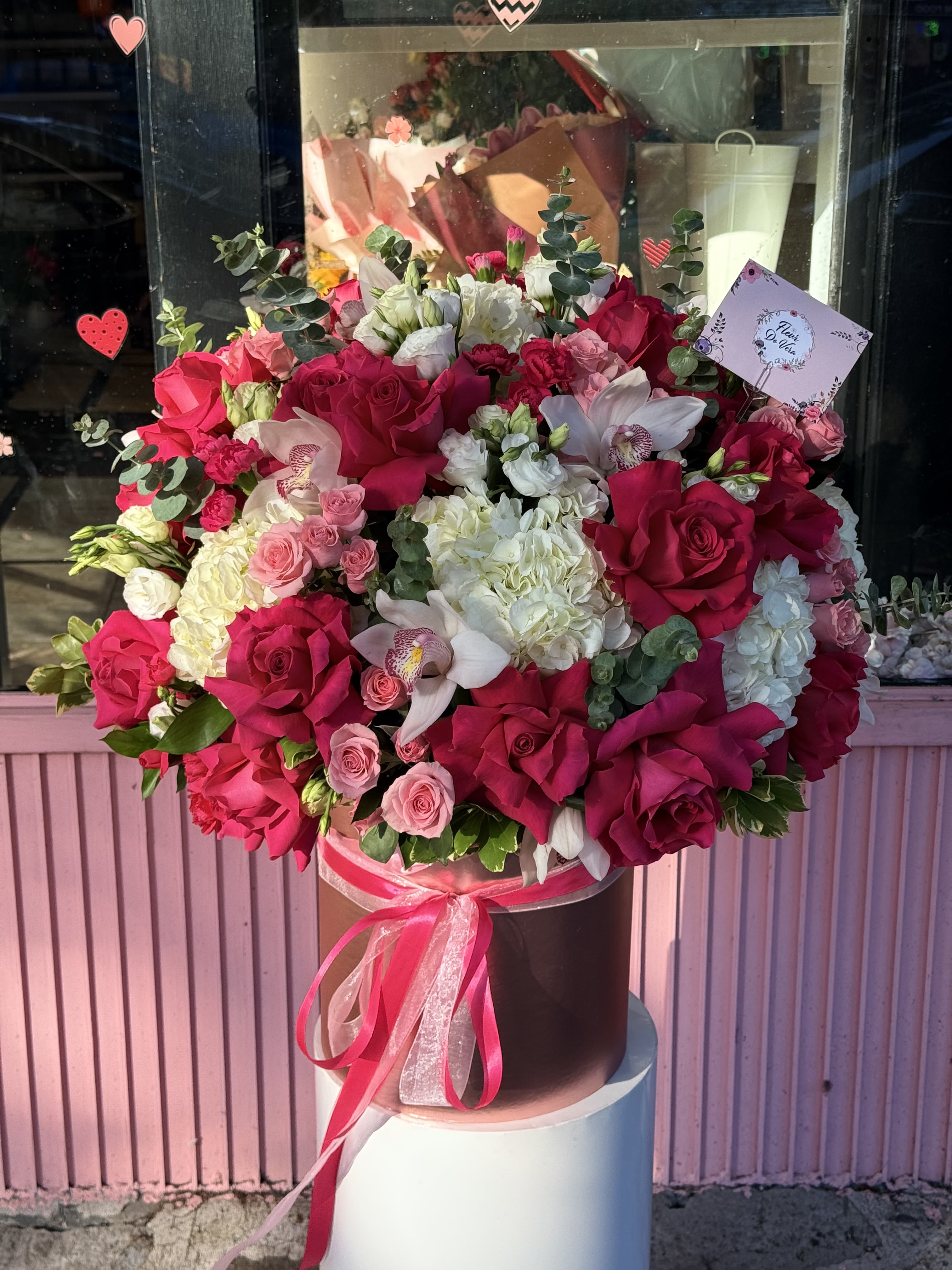 Large bouquet of pink and white roses with orchids in a hatbox