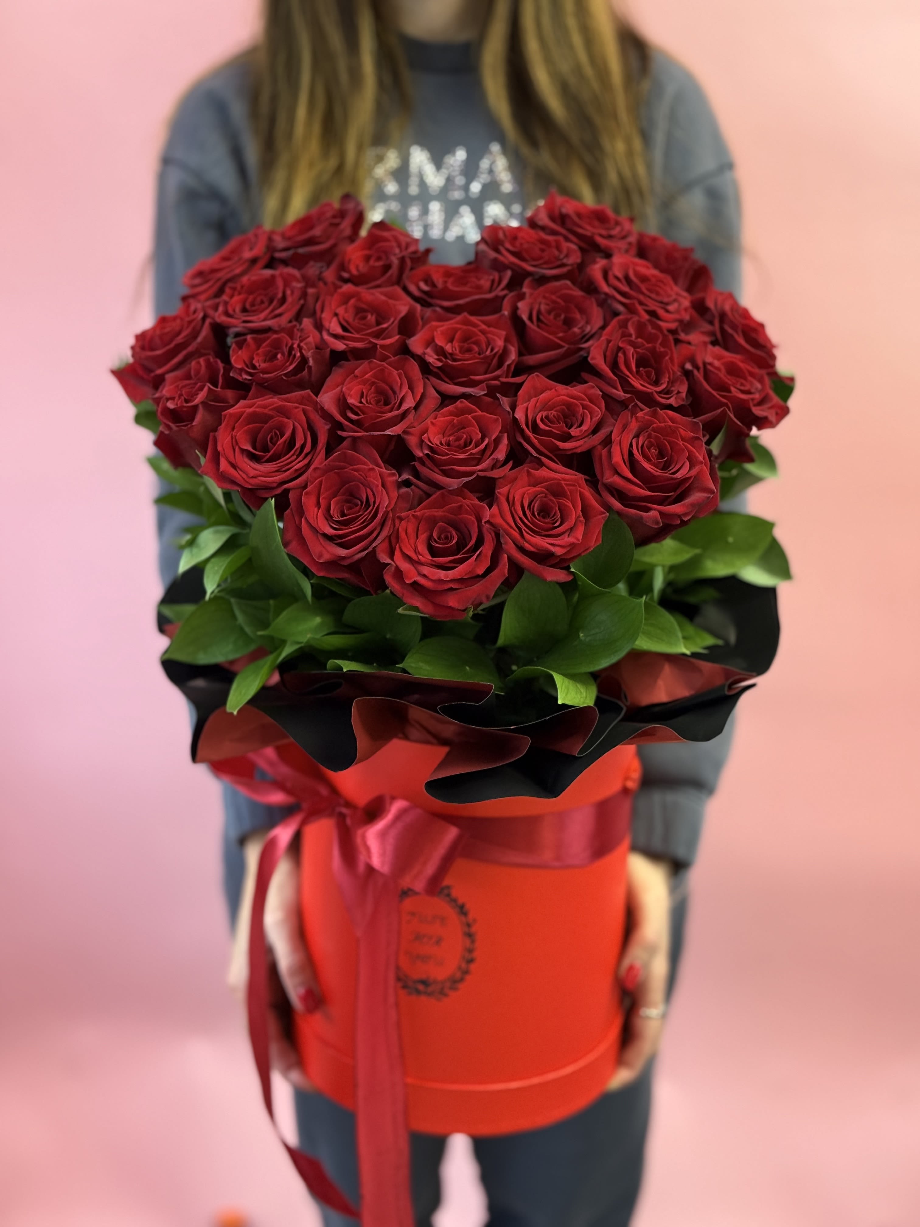 Large bouquet of red roses in a red hatbox with ribbon
